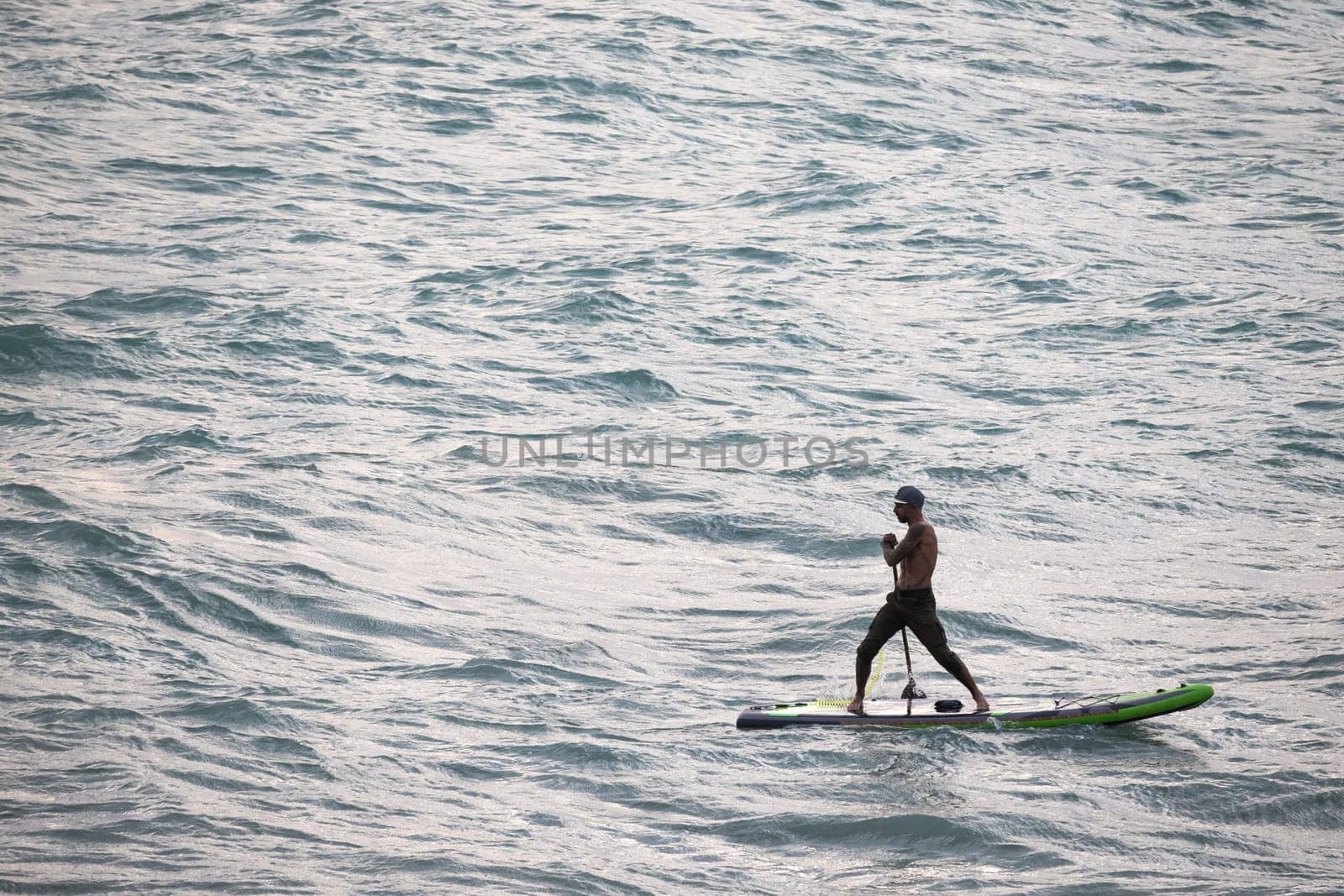 athletic wiry surfer guy swims with a paddle on sup board in the sea Stand up paddleboarding
