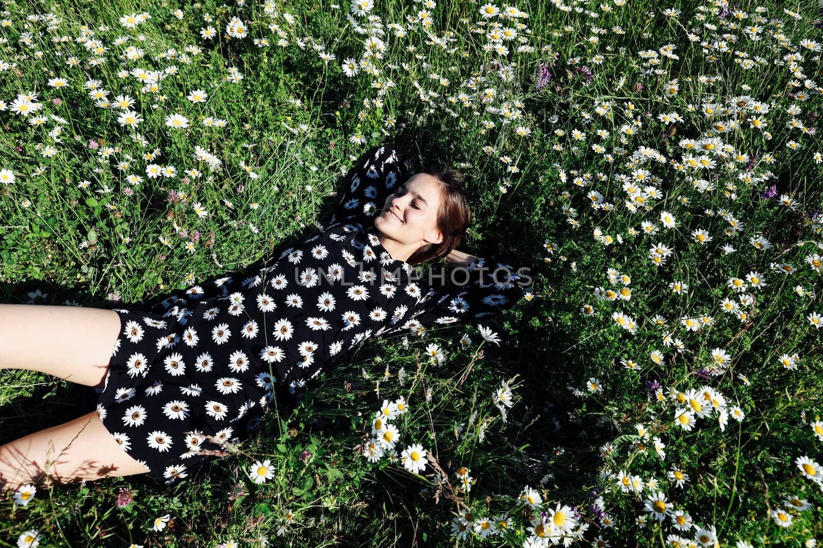 woman in a dress in a flower lies on a field with daisies