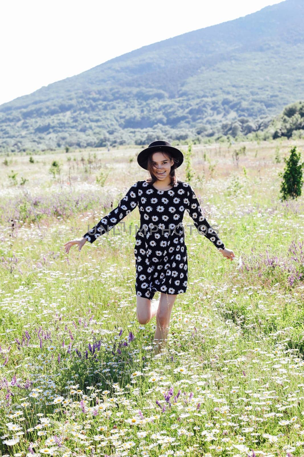 woman in a hat runs through a field of flowers in nature