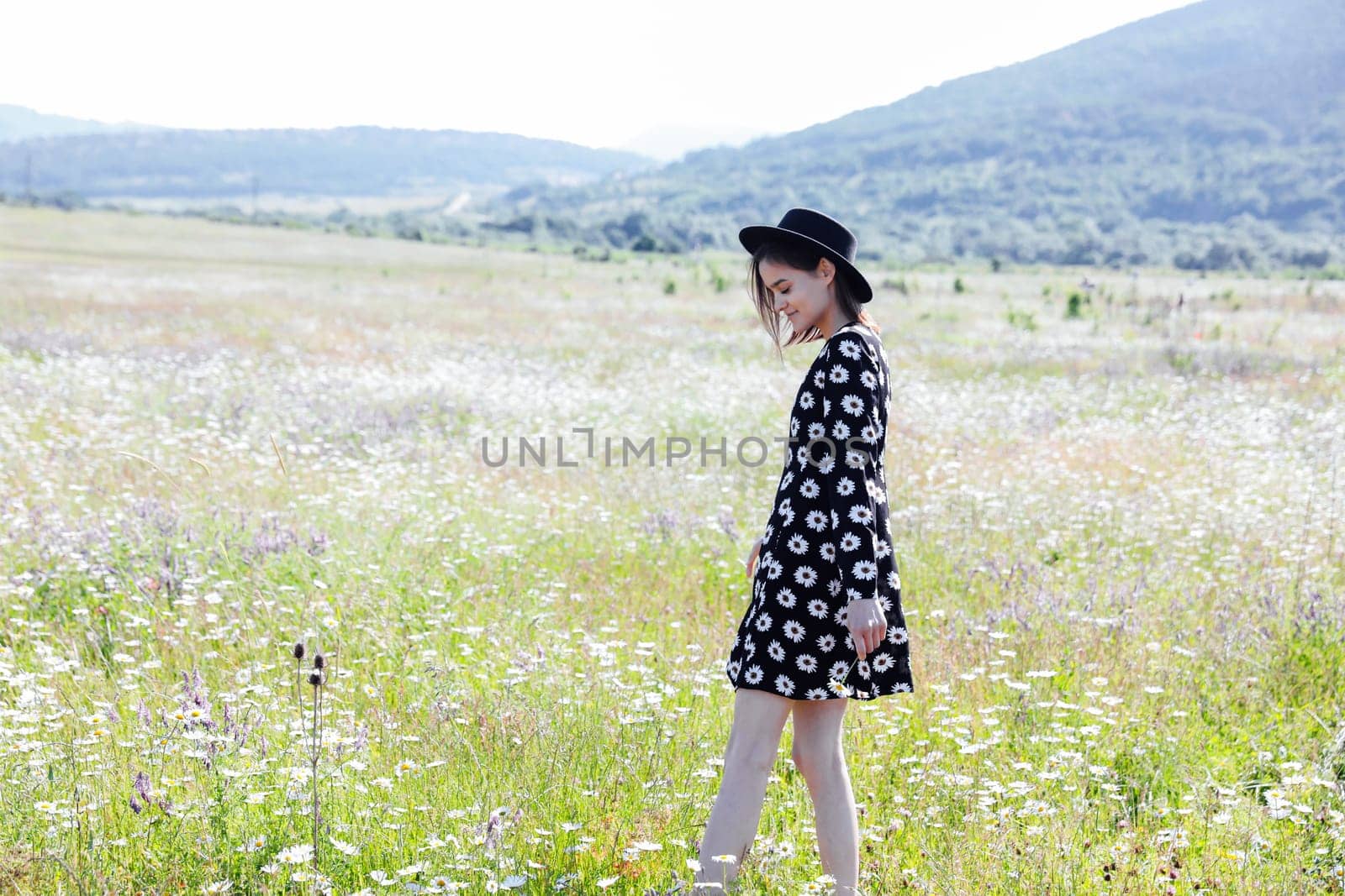 woman in a polka dot dress and a hat in nature on a walk in the field