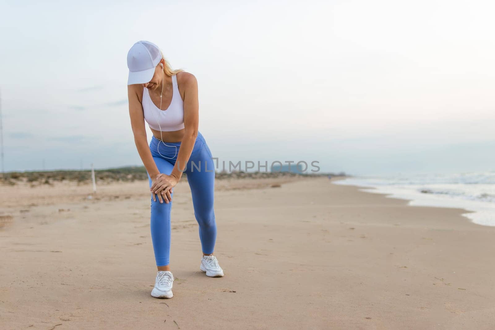 a girl of European appearance in sportswear does a warm-up at dawn on the sea, there is a place for an inscription. High quality photo