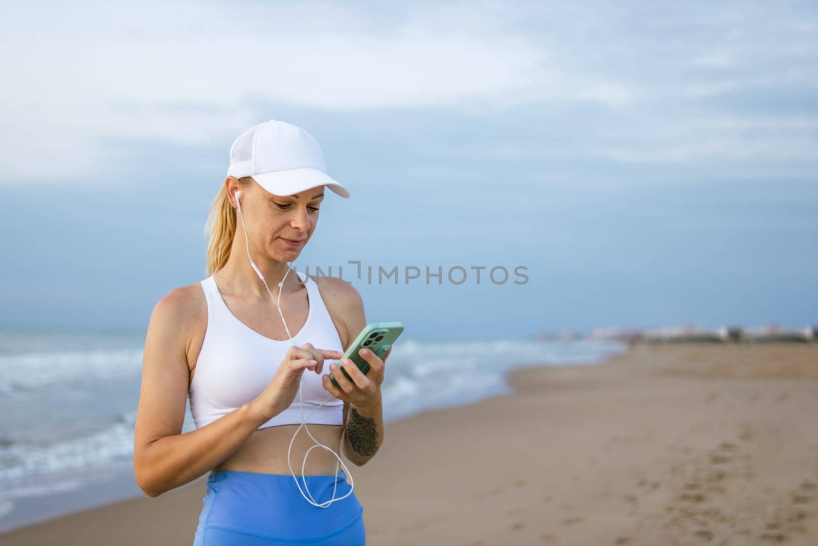 Close up photo of fit woman, using mobile phone at beach,there is a place for an inscription by PopOff