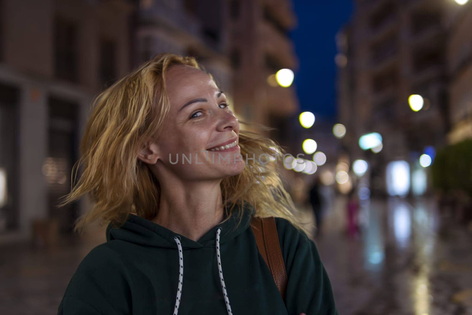 Beautiful girl smiles in the evening, the girl has blond hair, the girl shakes her head, selective focus. High quality photo