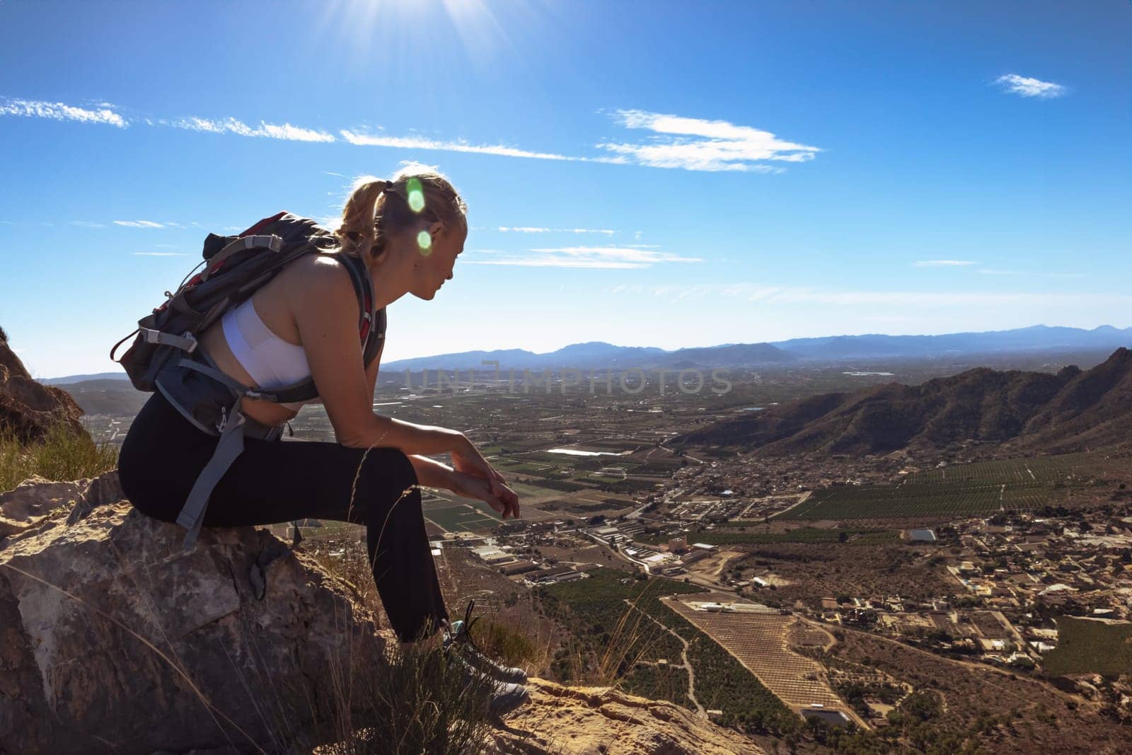 Hiking concept a girl in sportswear with a backpack sits on the mountain admiring the views. High quality photo