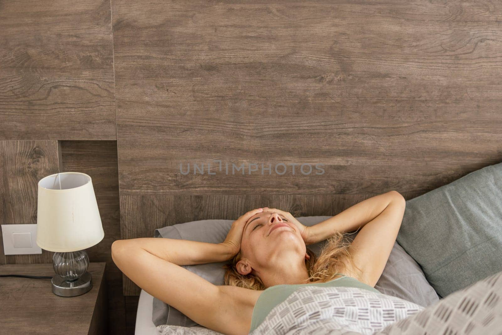 Pretty young woman on bed in modern apartment smiling after wake up by PopOff