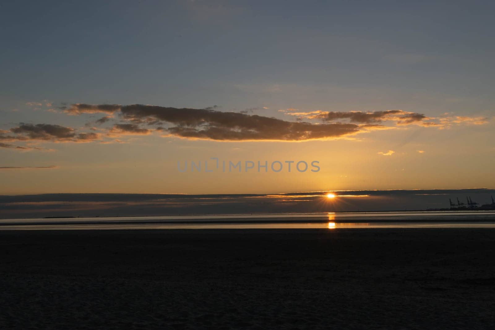 beautiful sunset on the shore of the sea the sky is golden in color due to the sun by PopOff