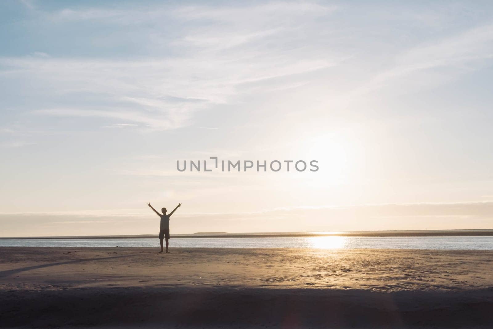 a child against the background of the sky, ocean and sand on the beach at sunset. Silhouette of a boy at sunset. Beautiful landscape there is a place for an inscription. High quality photo