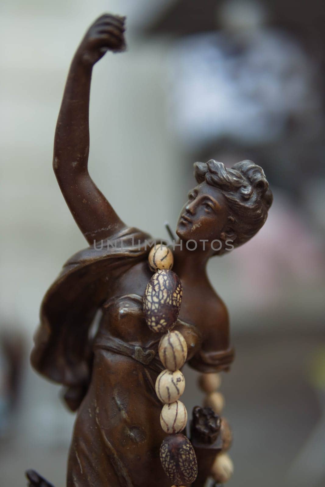 statue of a bronze-colored woman, sold at a fair in the city. Close-up of the statue. by PopOff