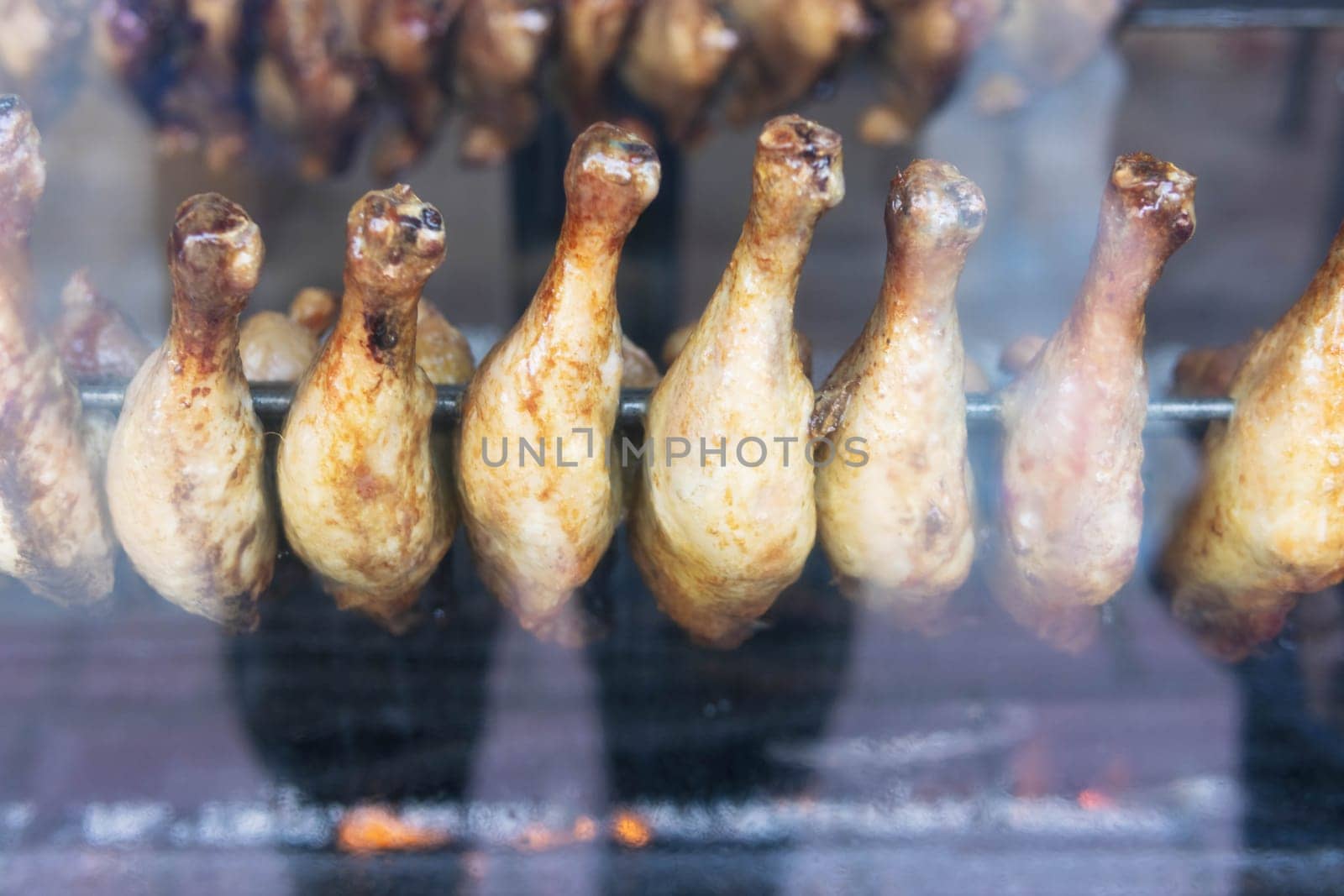 chicken legs are fried in a shop window for sale to hungry people by PopOff