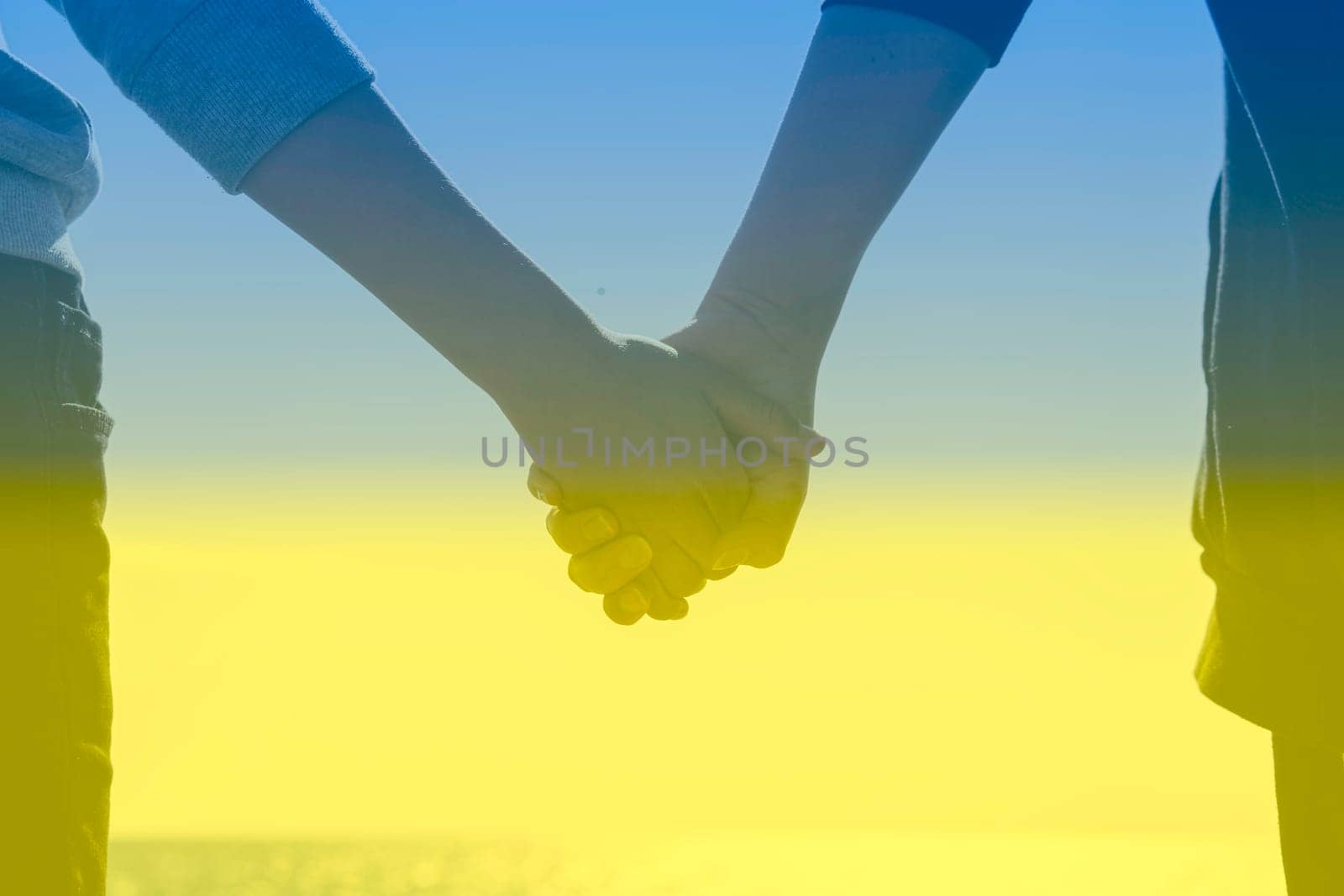 Children's hands hold against the background of the sky and the sea.the background on the photo is the flag of ukraine blue and yellow there is a place for the inscription. High quality photo