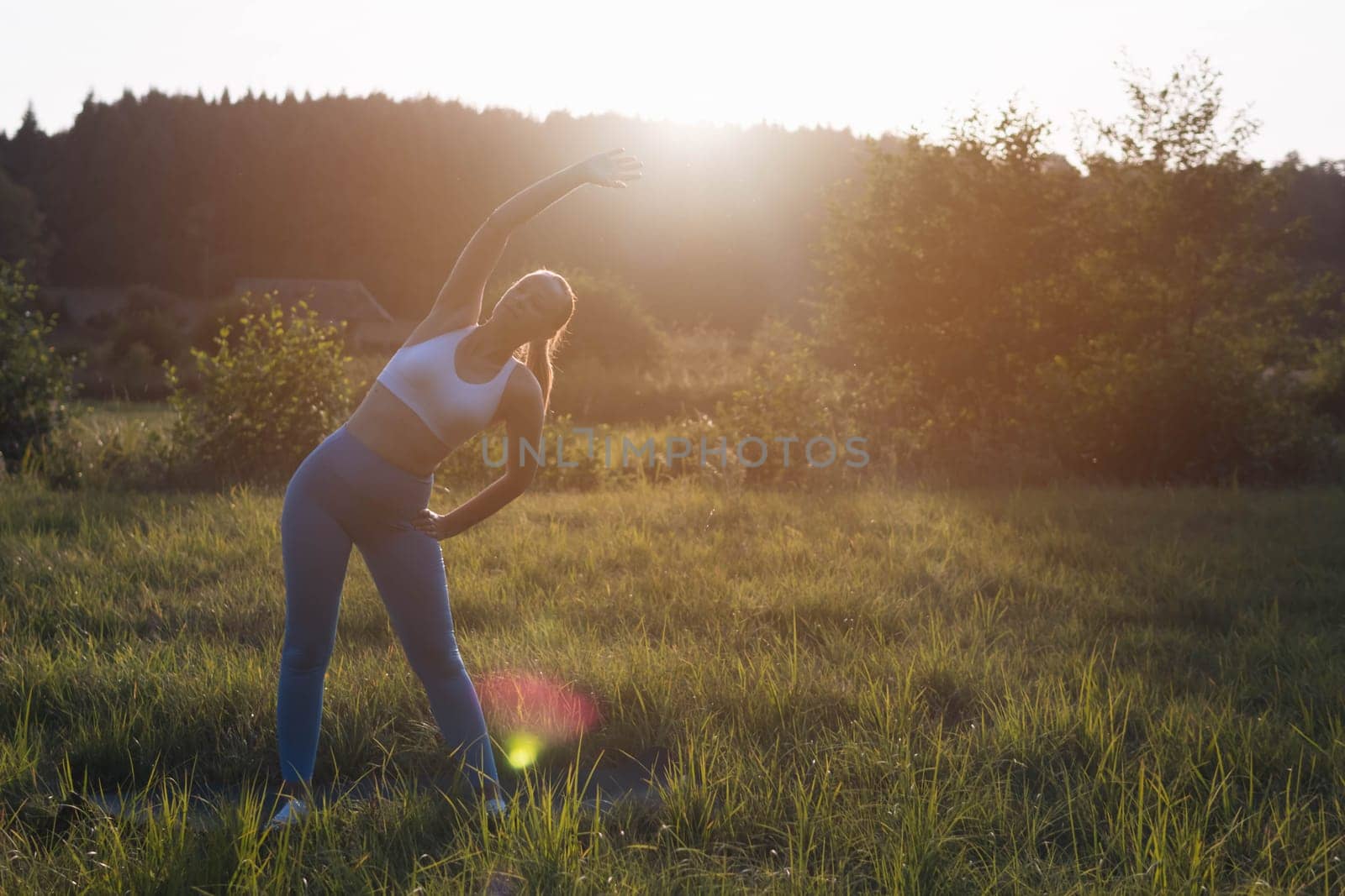 woman of light appearance in blue cleats and a white tank top is engaged in fitness in the park by PopOff