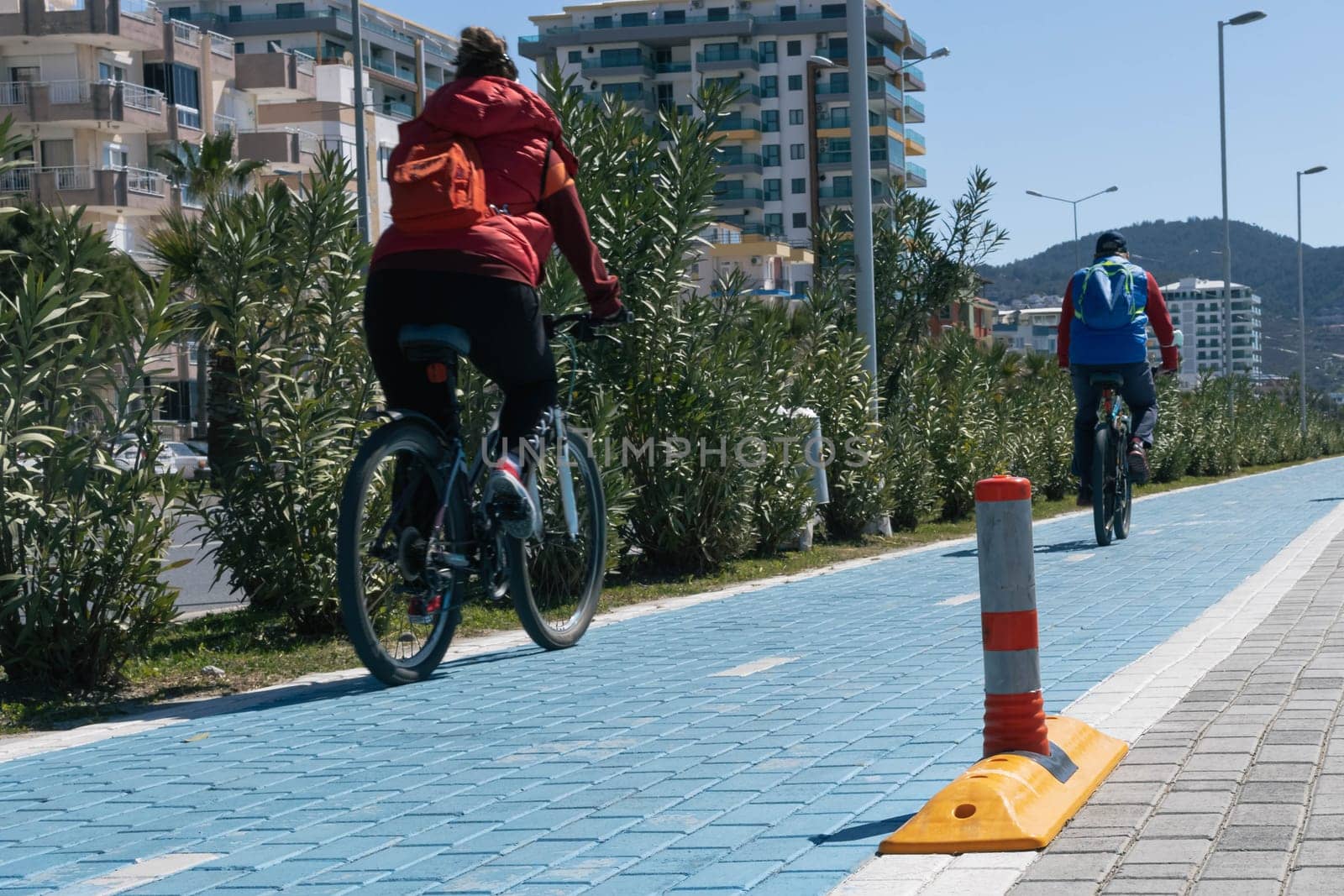 People travel on the street on bicycles on the track with markup. Bicycle track blue. High quality photo