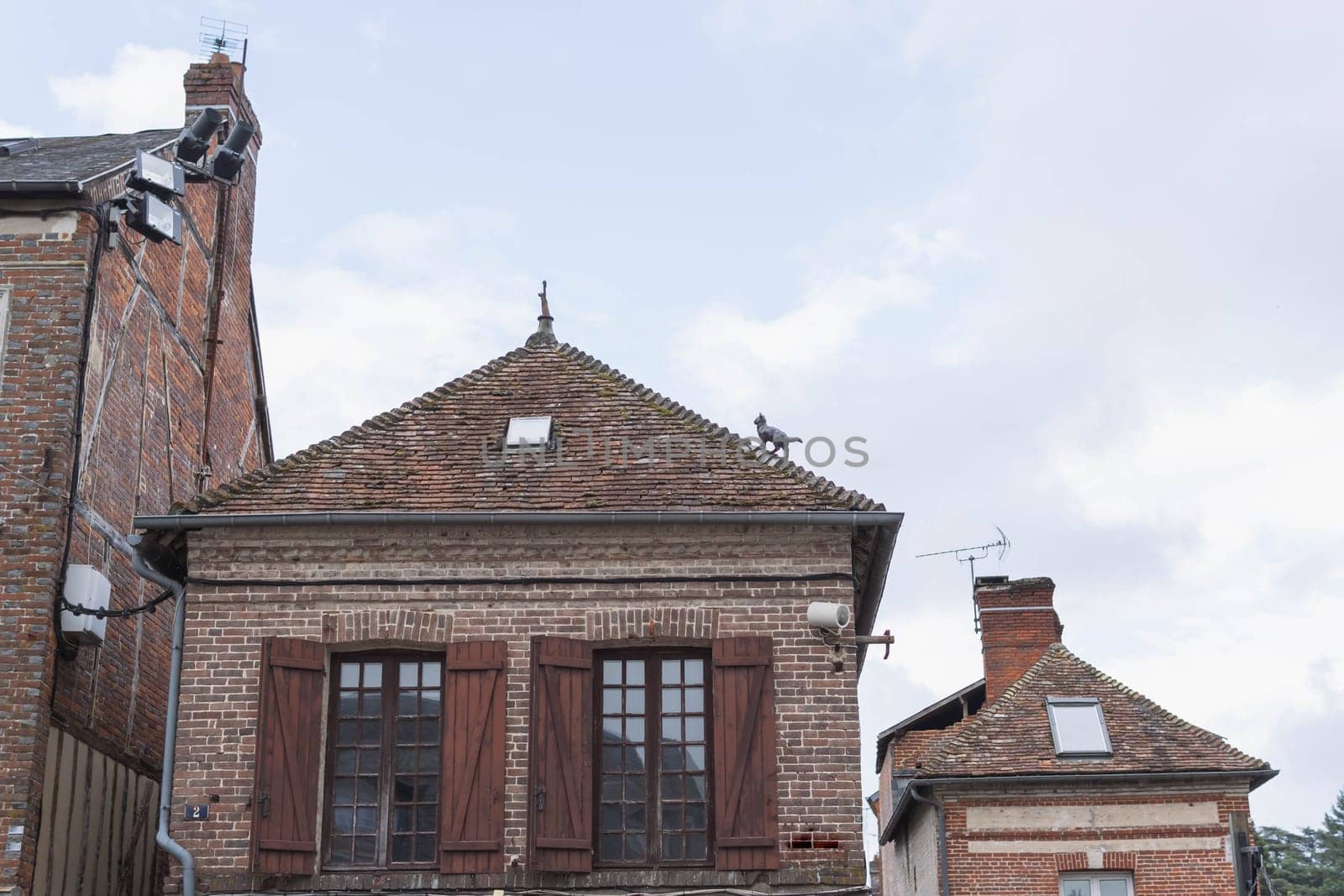 France,Normandy,Orbec. 11 June 2022 year. old house with red bricks on the roof statuette of a cat in Ville. High quality photo