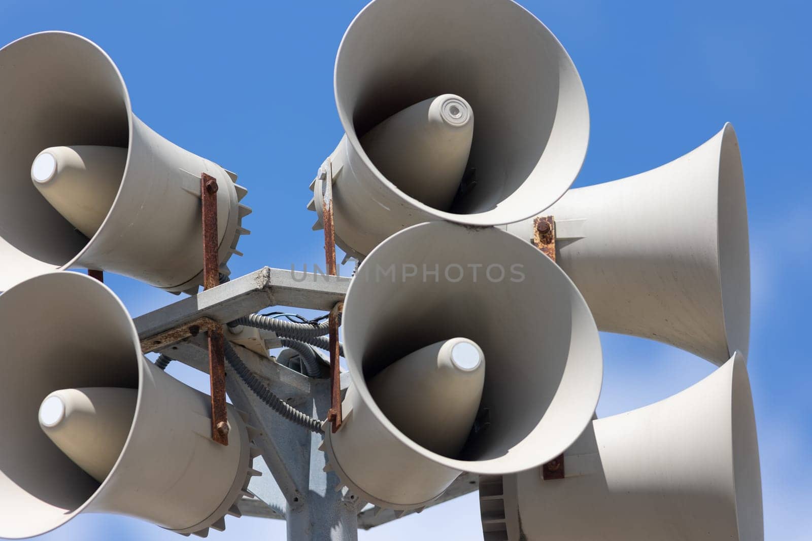 A large group of white speakers sitting on top of a metal pole