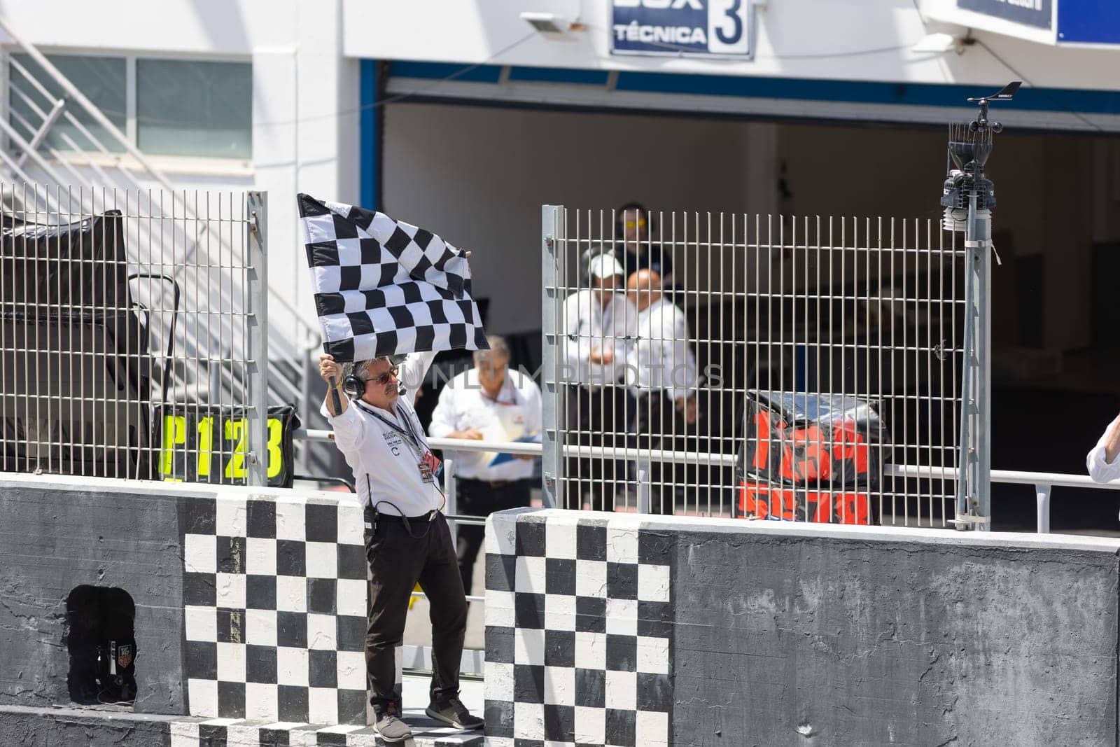 6 may 2023, Estoril, Portugal - MotoGP racing - A man holding a checkered umbrella standing on top of a race track