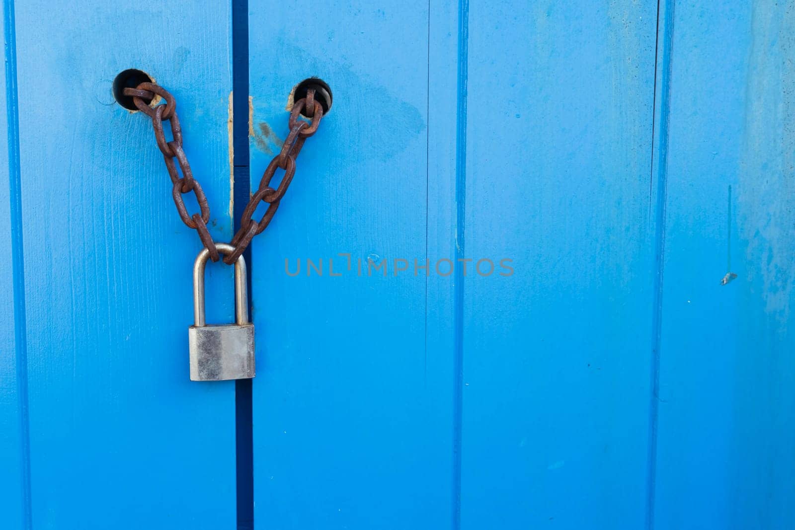 Lock on a blue door with a chain on the right there is a place for an inscription. High quality photo