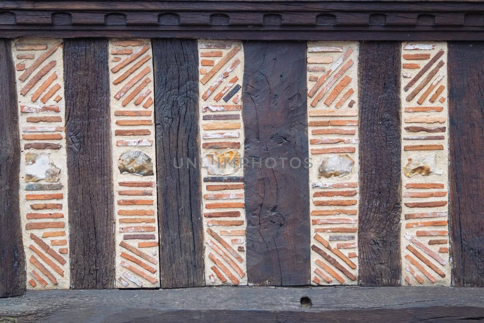 old house wall with decor elements - brown wooden boards and orange inserts in the plaster. High quality photo close up