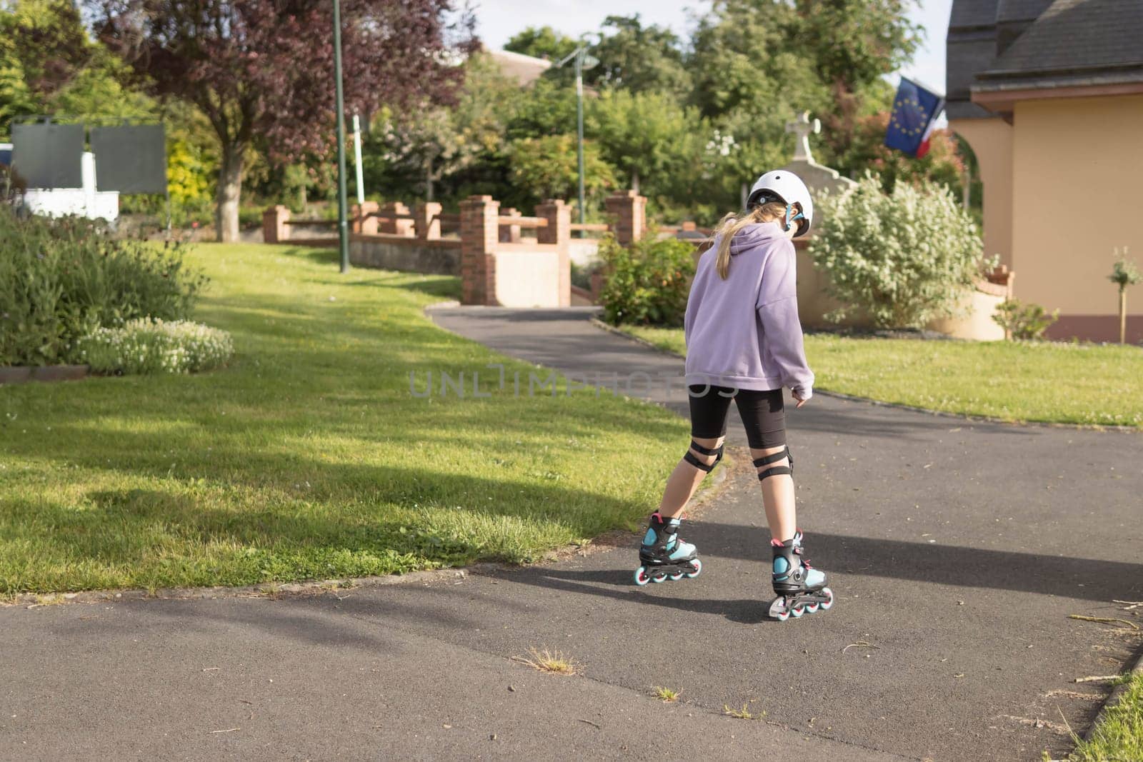 a child learns to roller skate in the park a dressed girl in a lilac sweater by PopOff