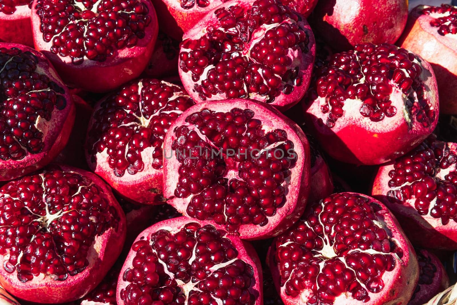 a lot of ripe red pomegranates with a cut off top, close-up background by PopOff