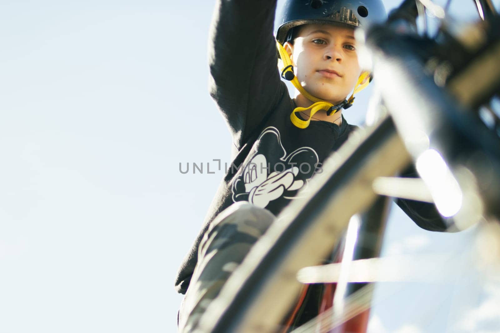 a teenager boy of European appearance with short blond hair in a T-shirt stands with a bicycle in the park.looks at the camera on the left there is a place for an inscription. High quality photo