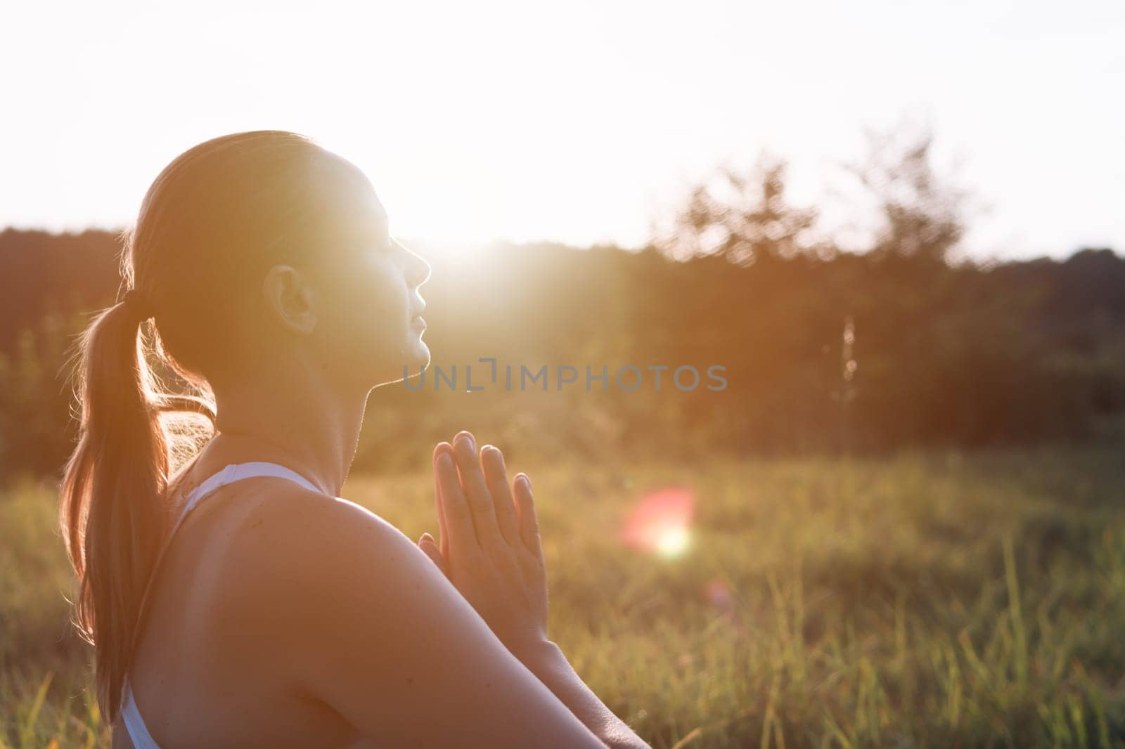 silhouette of a girl of European appearance at sunset, a round plan on the face, there is a place for an inscription on the side, the girl is doing yoga. High quality photo