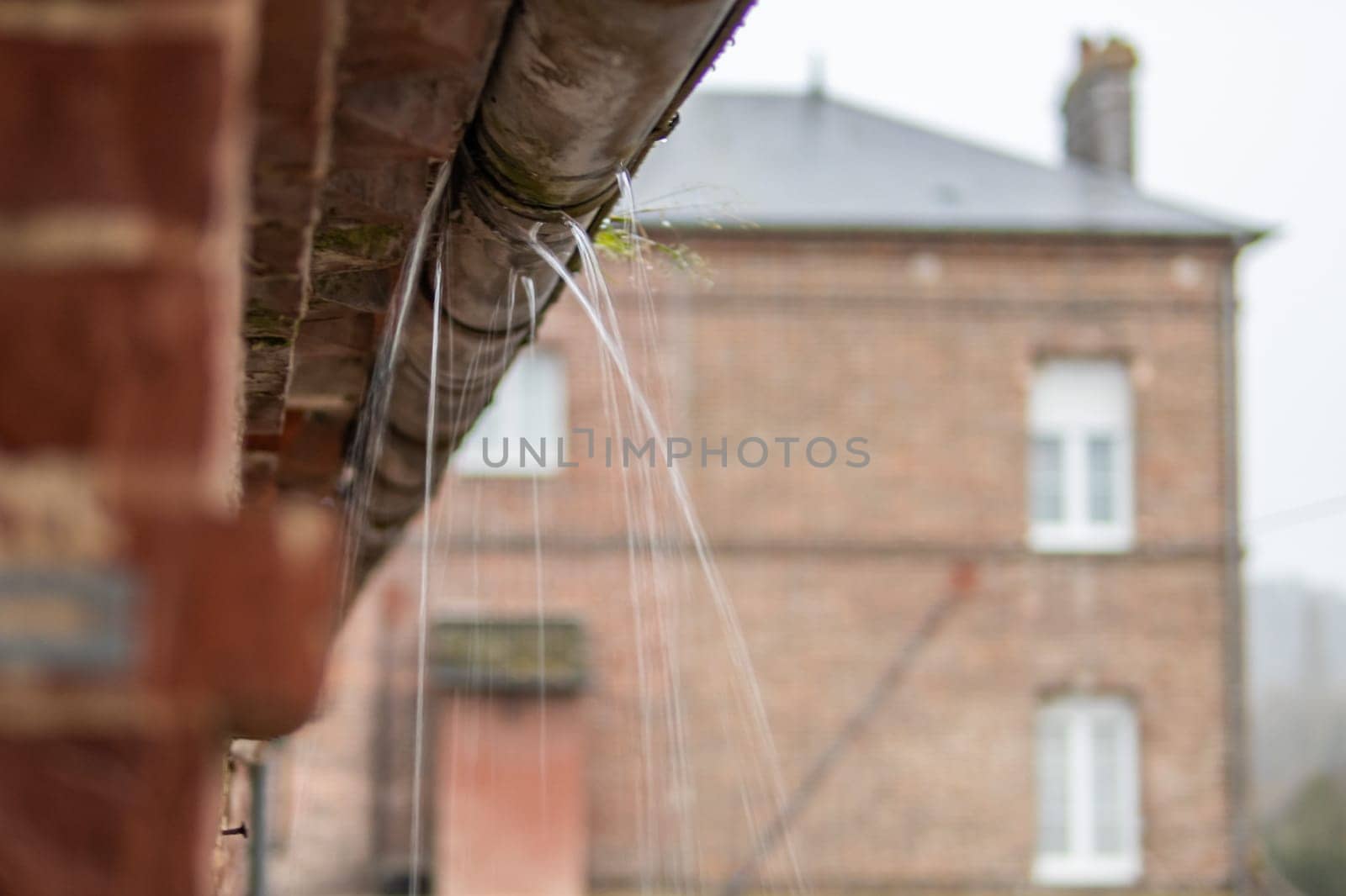 a gutter on a building, an old drainpipe close-up, water flows through rotten metal, there is a place for an inscription by PopOff