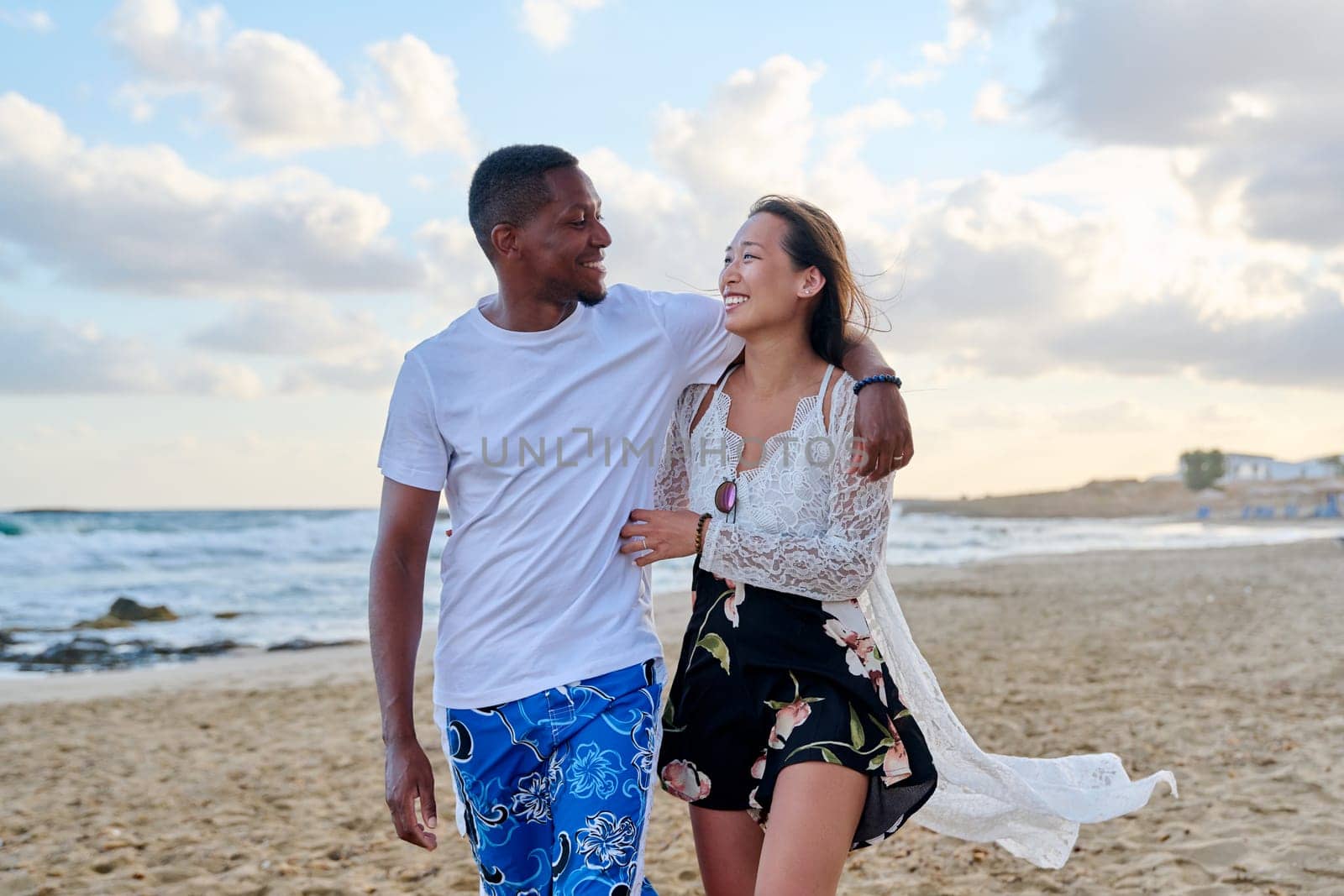 Young happy couple walking on the beach holding hands. by VH-studio