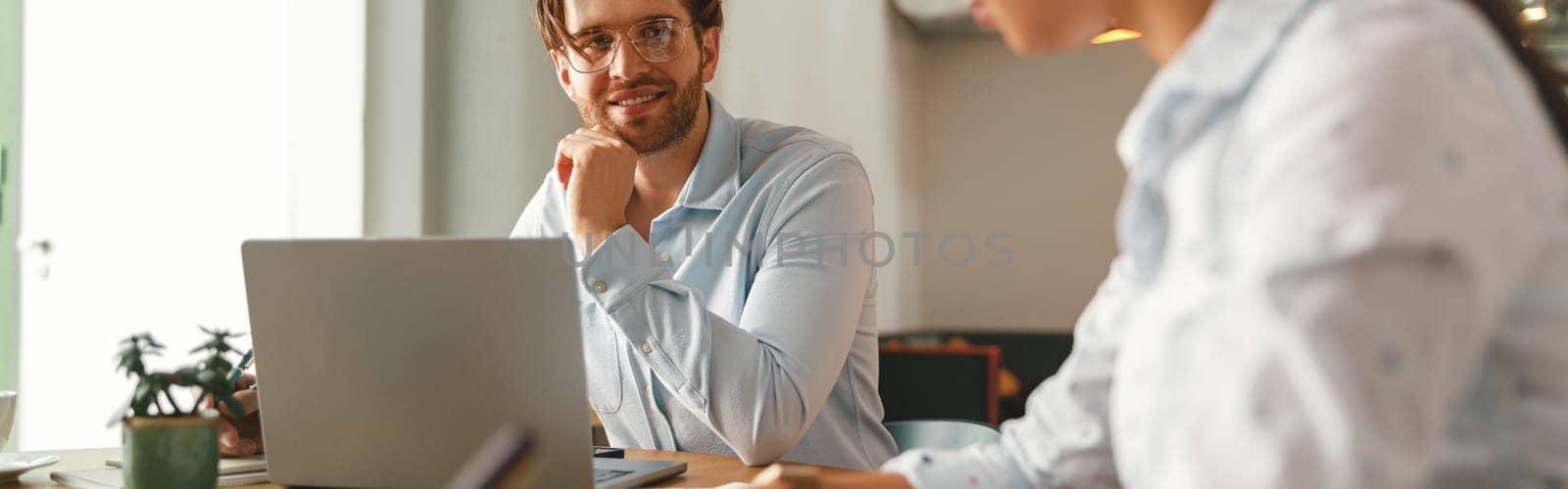 Two coworkers working together on project while using laptop in office meeting room