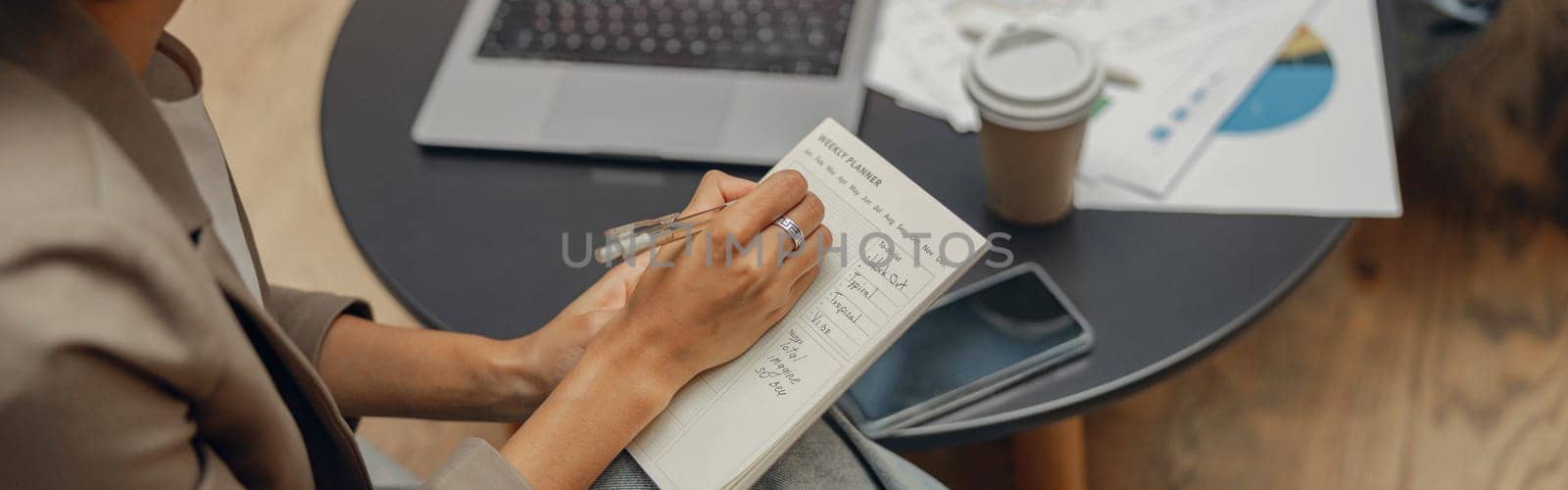 Close up of woman writing something down while sitting with colleague in modern office by Yaroslav_astakhov