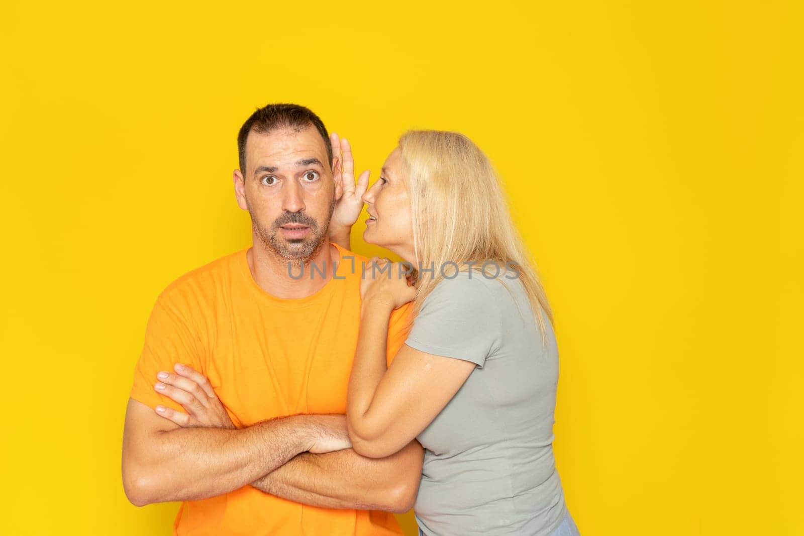 Relationships, love and couple concept: smiling girlfriend telling the secret to her boyfriend in his ear.