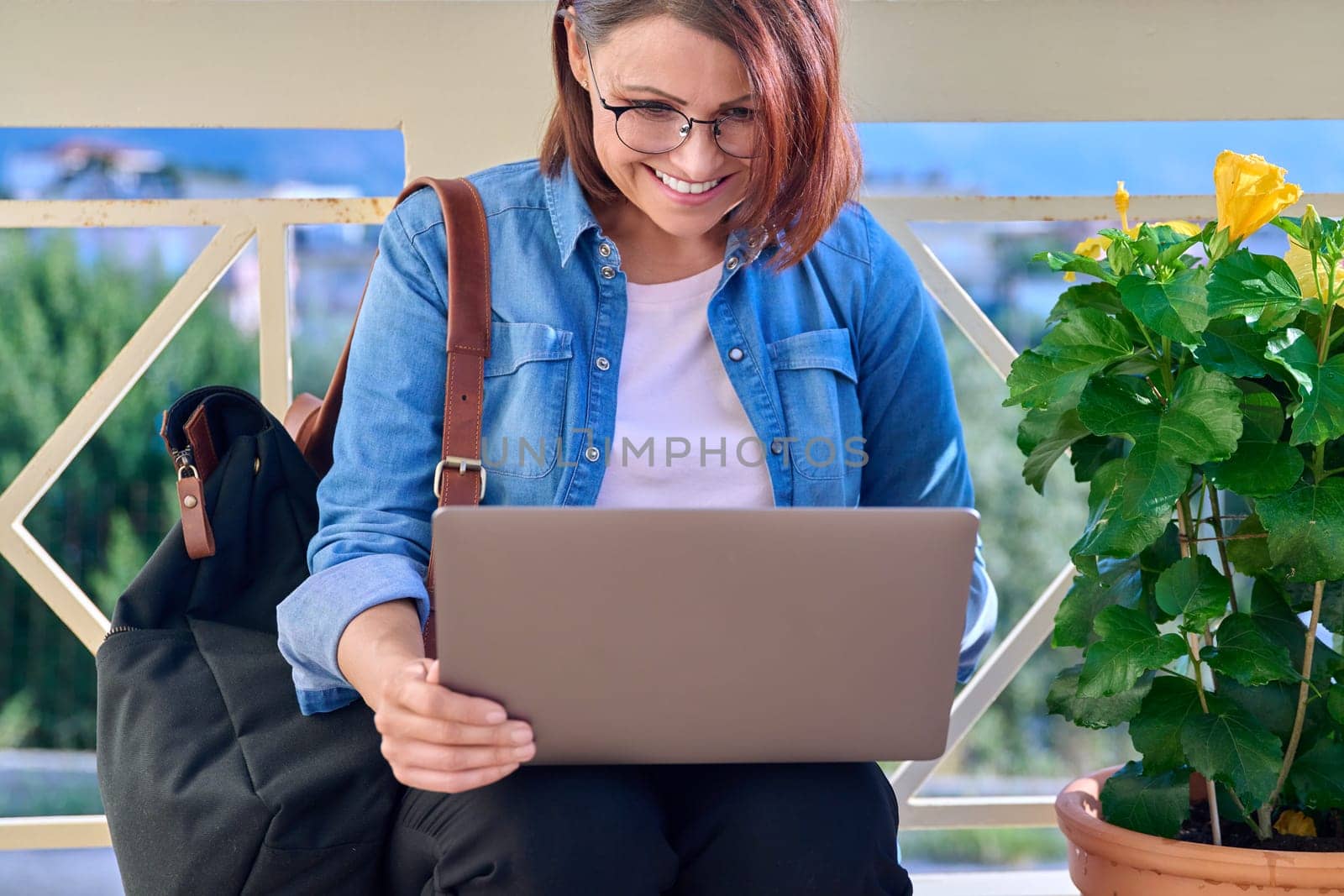 Positive smiling middle-aged business woman with laptop outdoors. by VH-studio