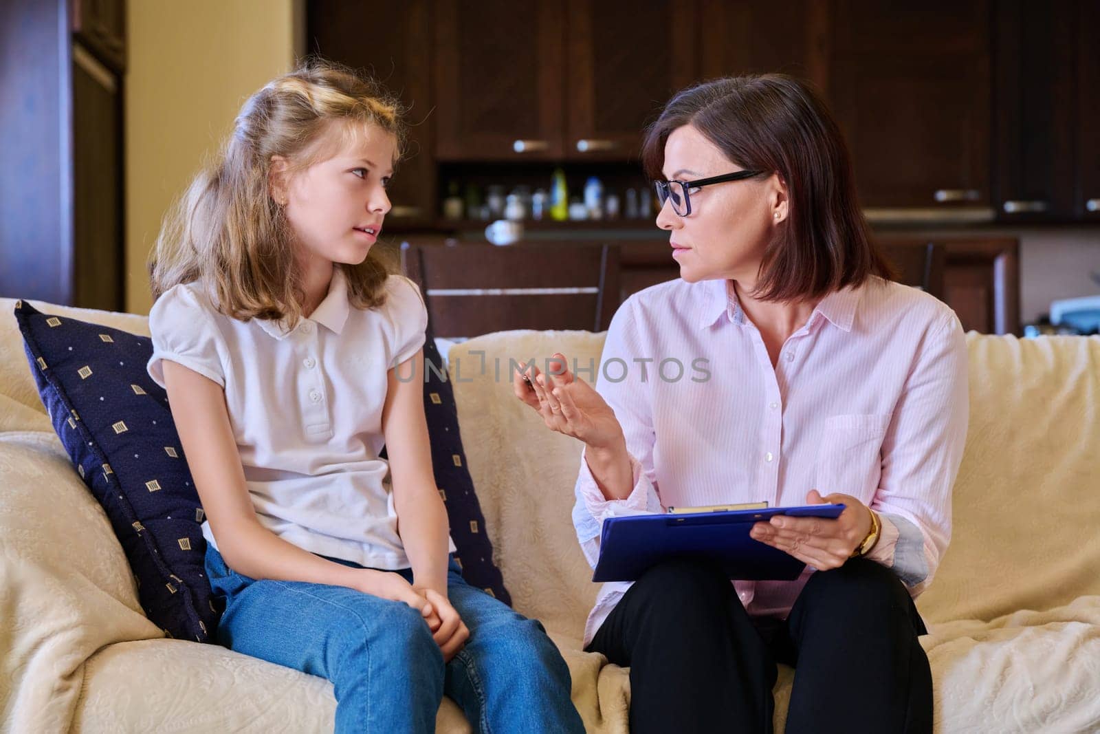 Woman social worker talking to baby girl, meeting session at home on sofa. Psychology, education, children, help, mental health concept