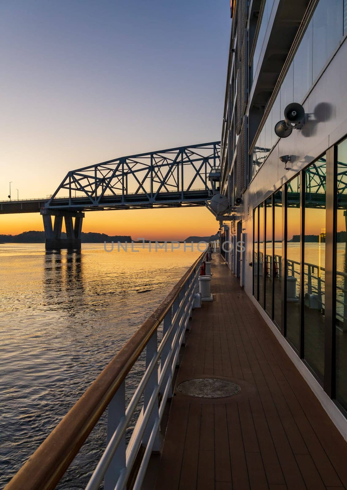 Mississippi river cruise boat sails towards Mark Twain Memorial road bridge near Hannibal, Missouri at sunrise
