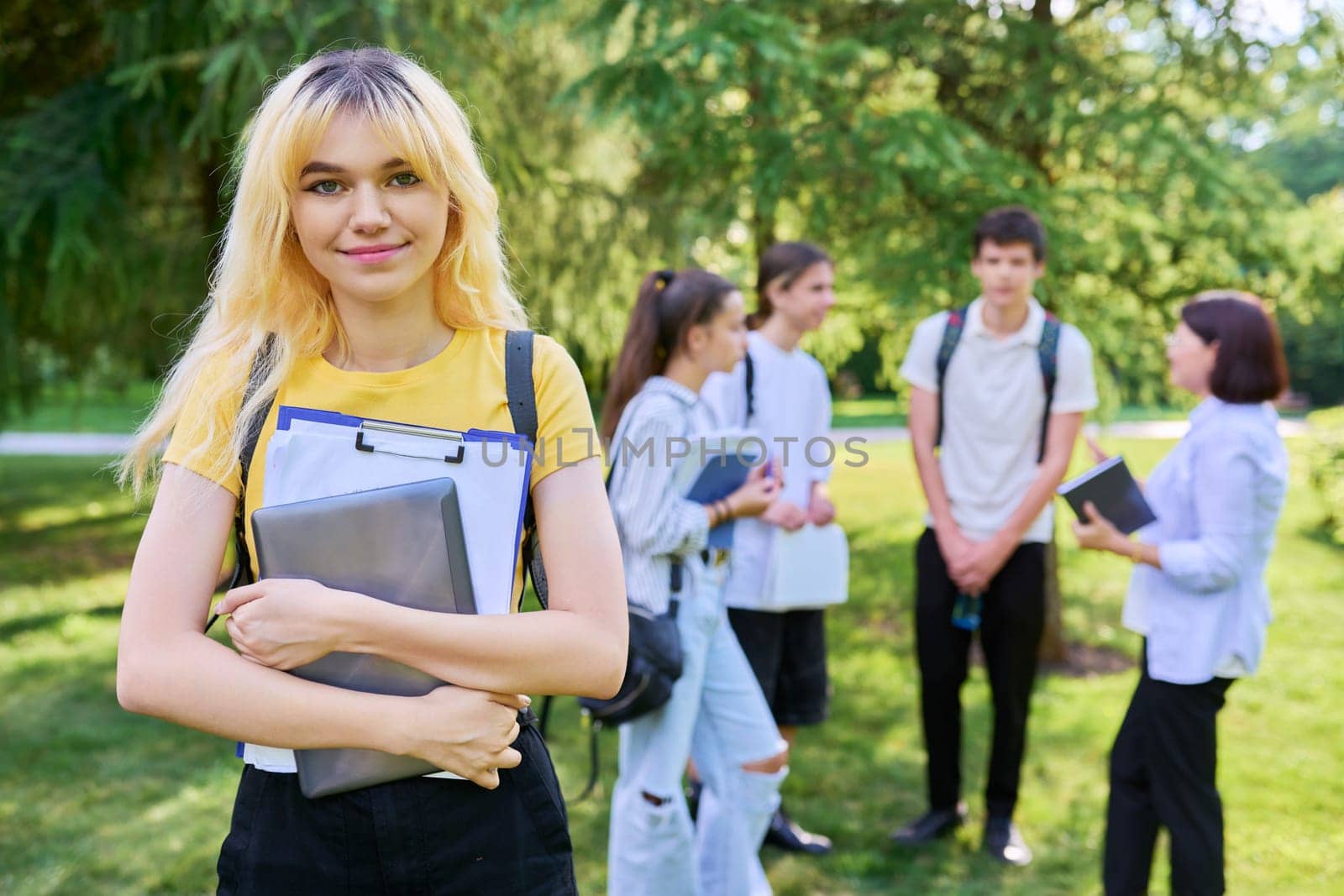Female student 16, 17 years old with textbooks backpack, in school park by VH-studio