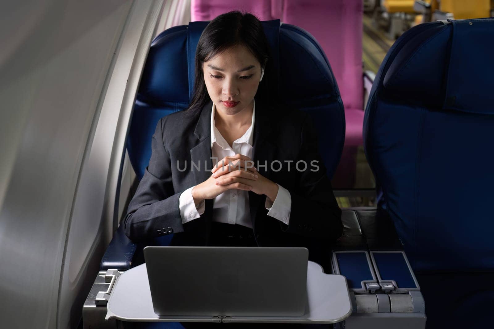 Beautiful Asian businesswoman working with laptop in aeroplane. working, travel, business concept by itchaznong