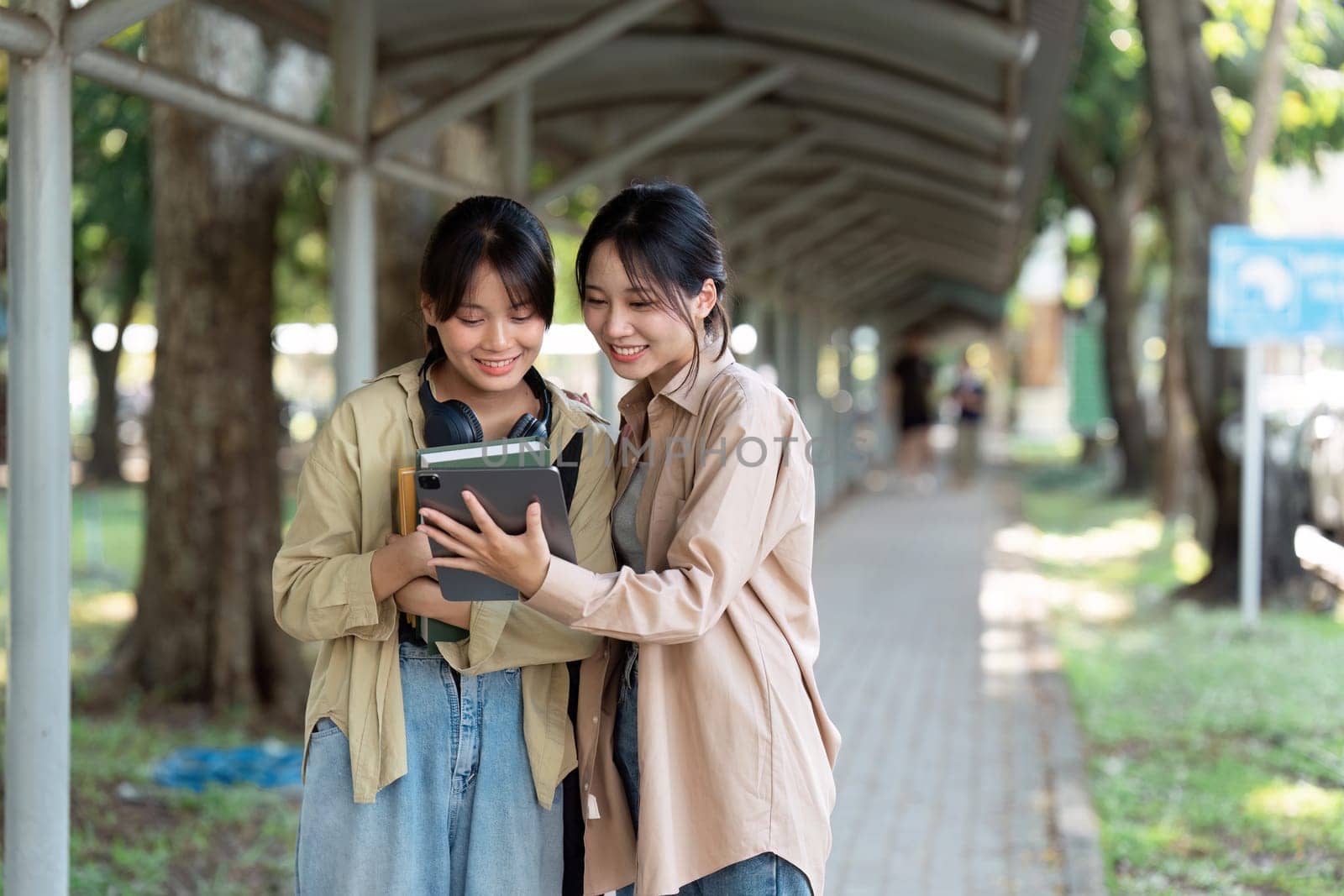 university students using a digital tablet while walking to next class by itchaznong