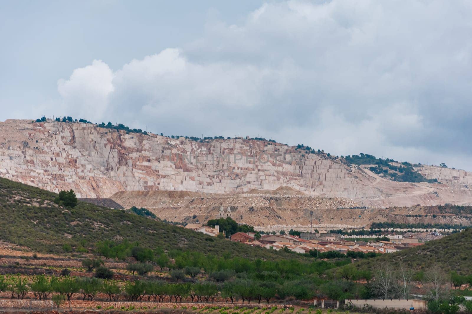 view of an open pit marble quarry showing heavy duty equipment and rock. by PopOff