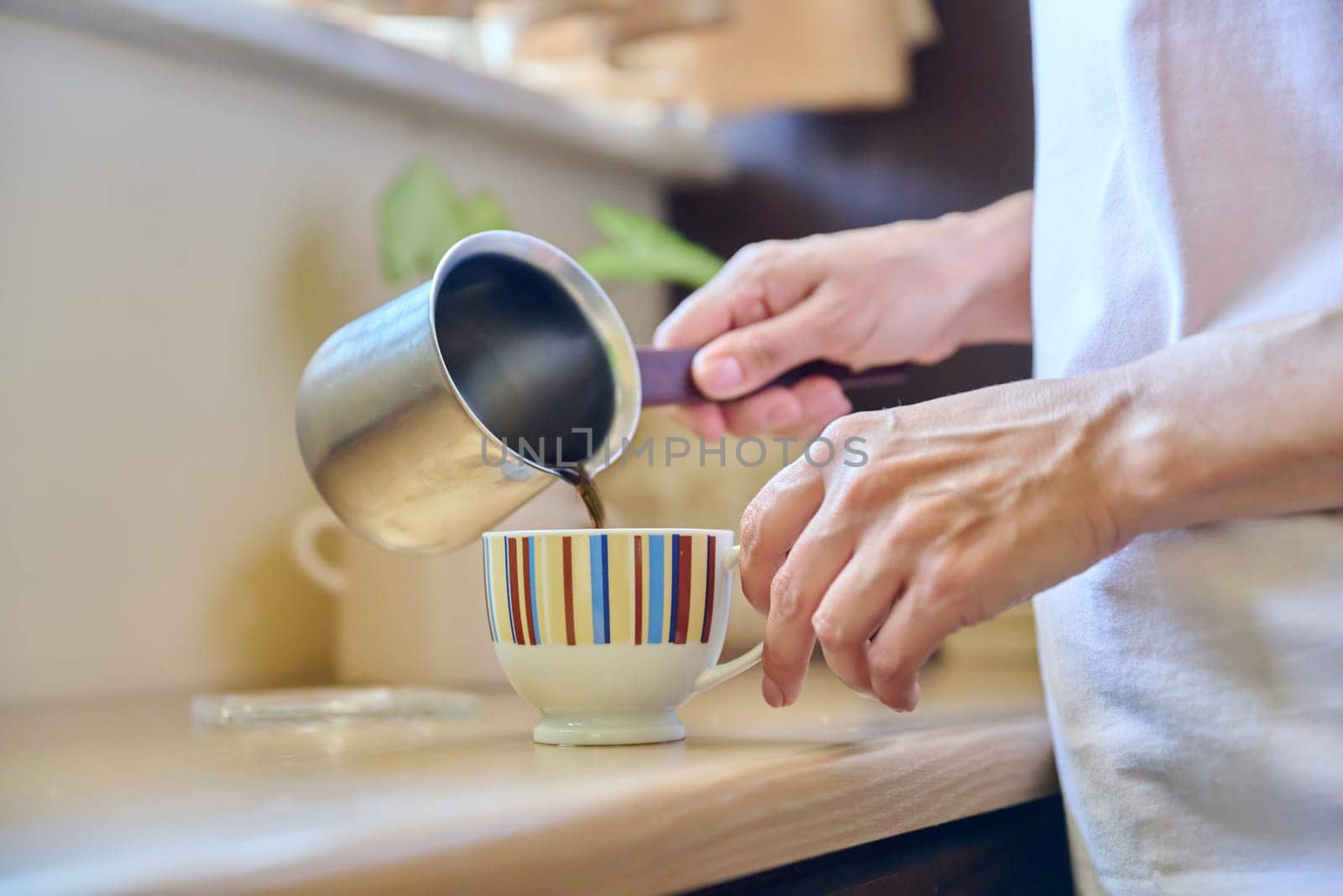 Close-up of a woman's hands preparing coffee in an iron cezve. by VH-studio