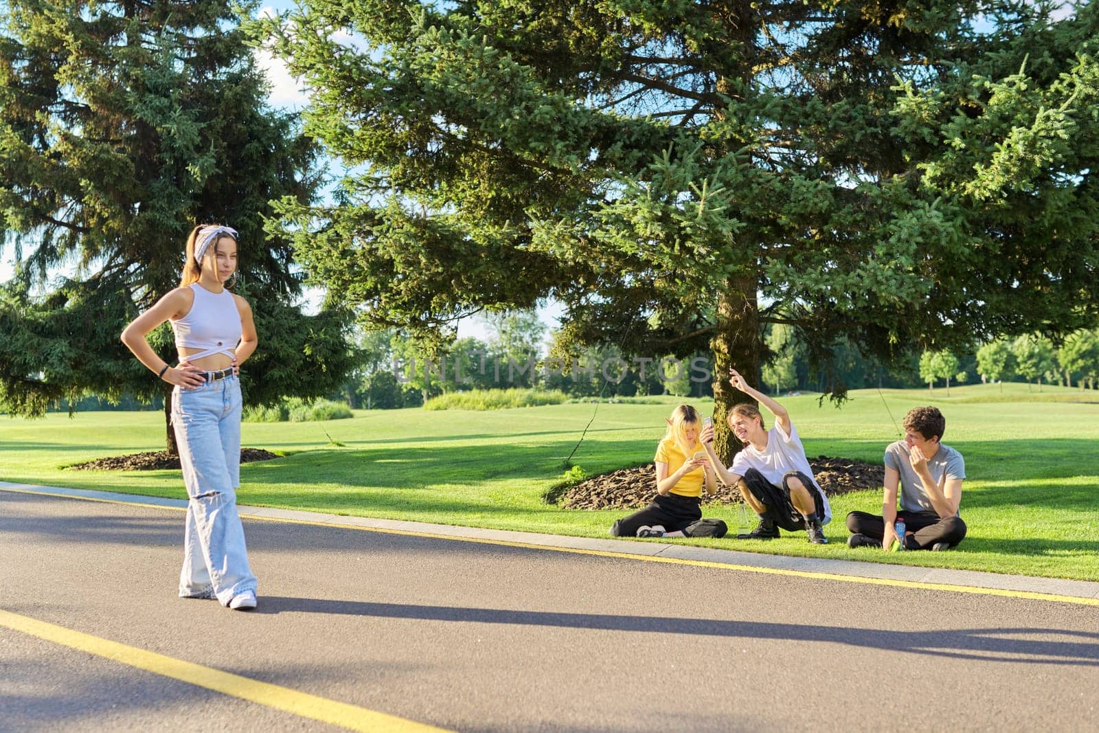 Group of hipsters teenagers having fun in park on road, teenage girl dancing street dance, friends filming video on smartphone. Vacation, leisure, friendship, lifestyle, teenagers concept