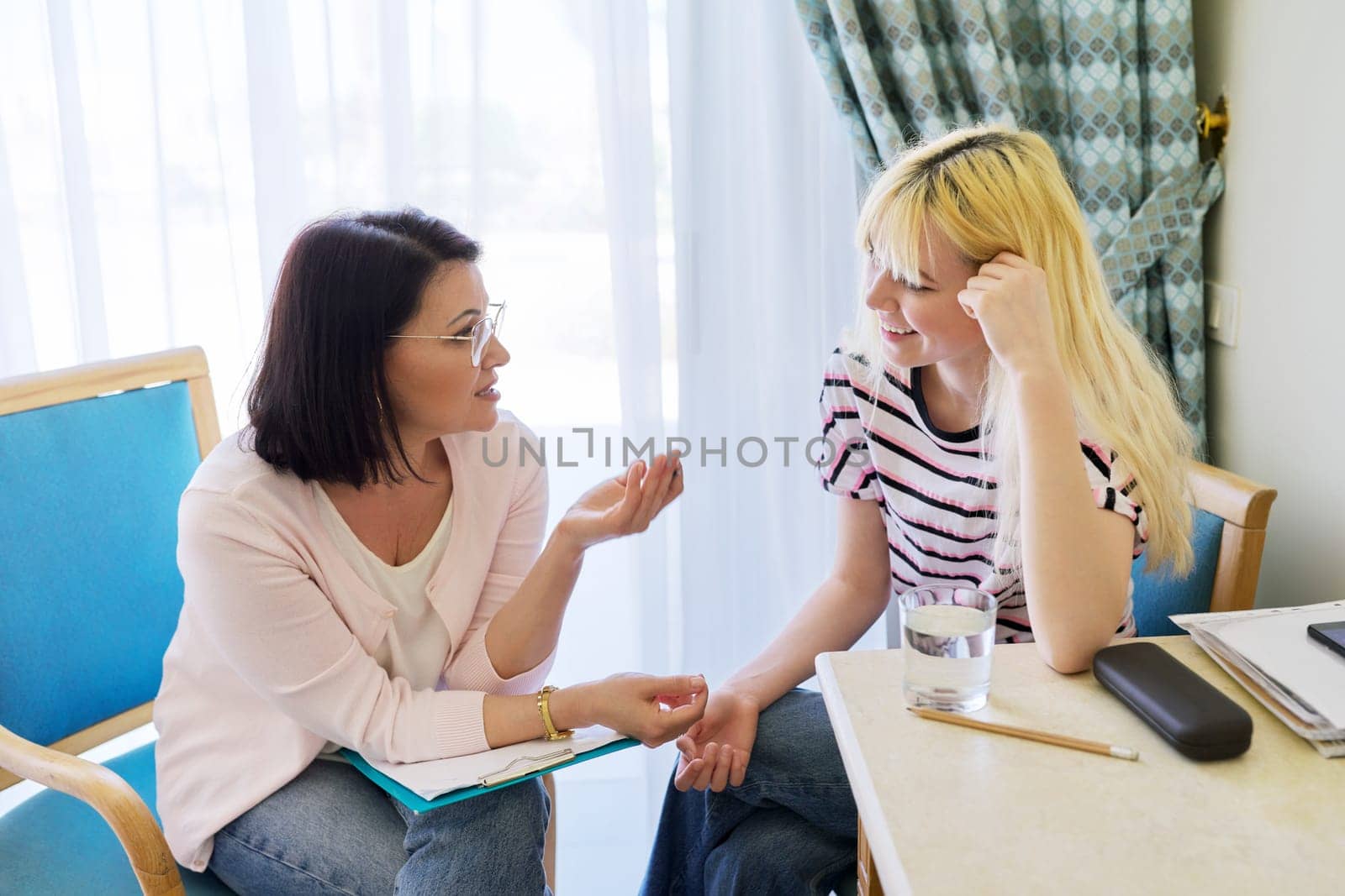Woman teacher, therapist, social worker talking to teenage student in the office. by VH-studio