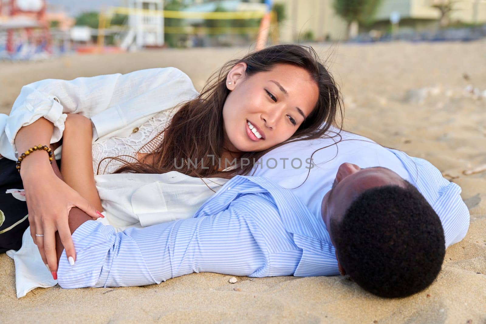 Young happy couple lying on the sand, top view by VH-studio