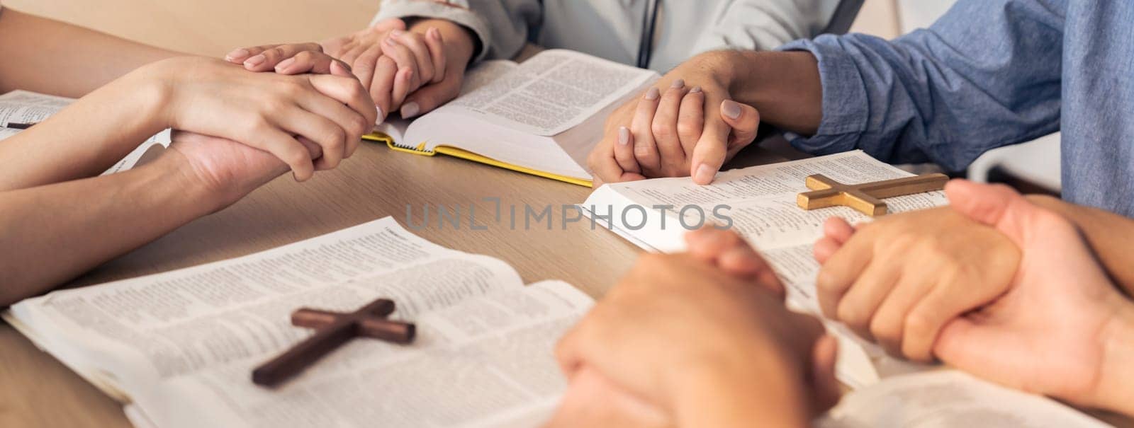 Cropped image of diversity people hand praying together at wooden church on bible book while hold hand together with believe. Concept of hope, religion, faith, god blessing concept. Burgeoning.