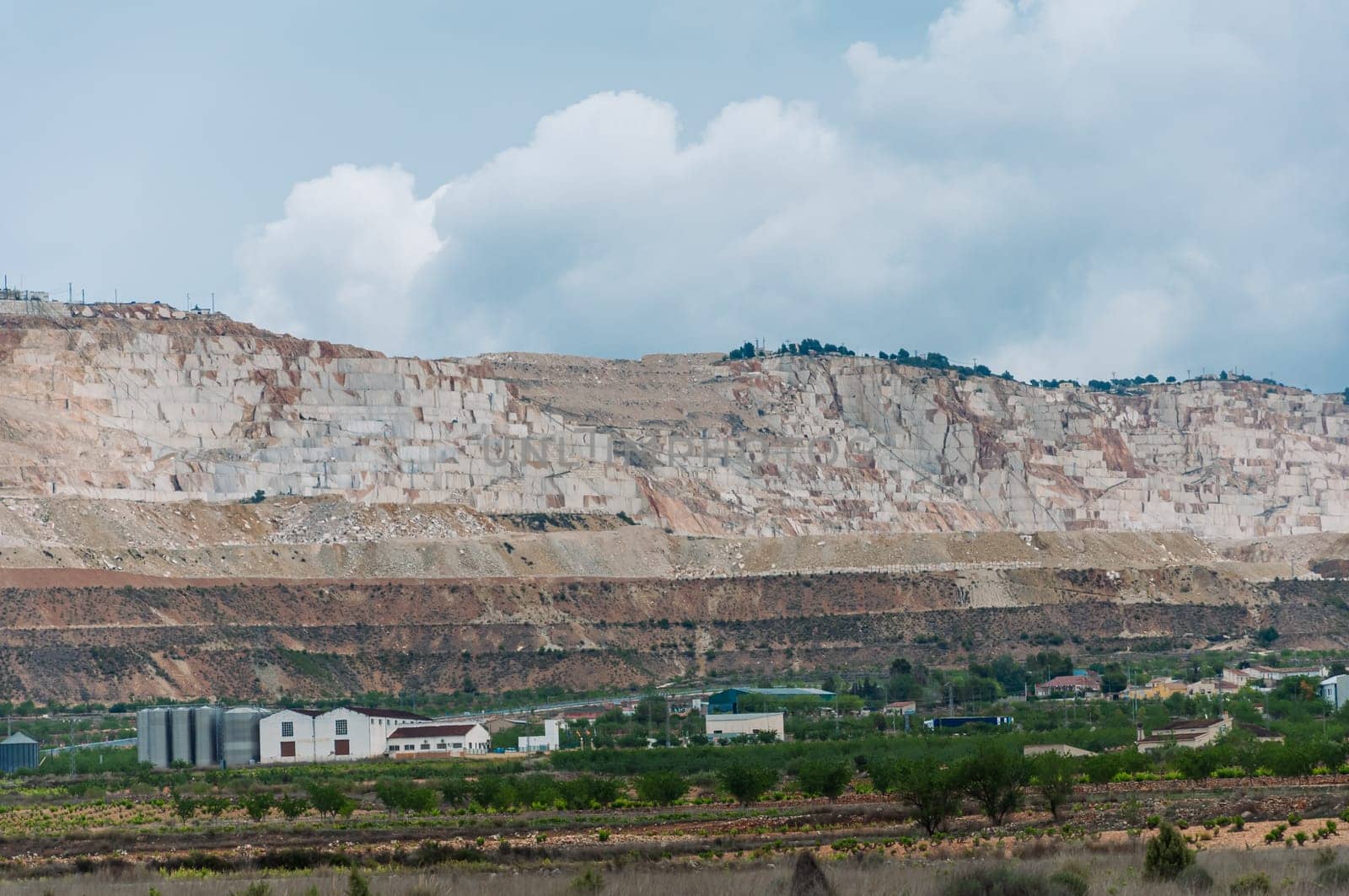 view of an open pit marble quarry showing heavy duty equipment and rock. High quality photo