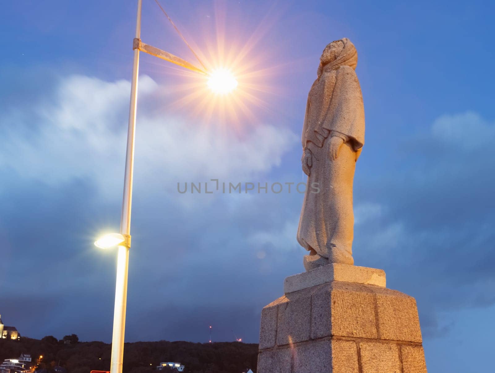 a statue of a woman standing close-up in the evening city, a lantern shines on the statue. There is a place for an inscription by PopOff