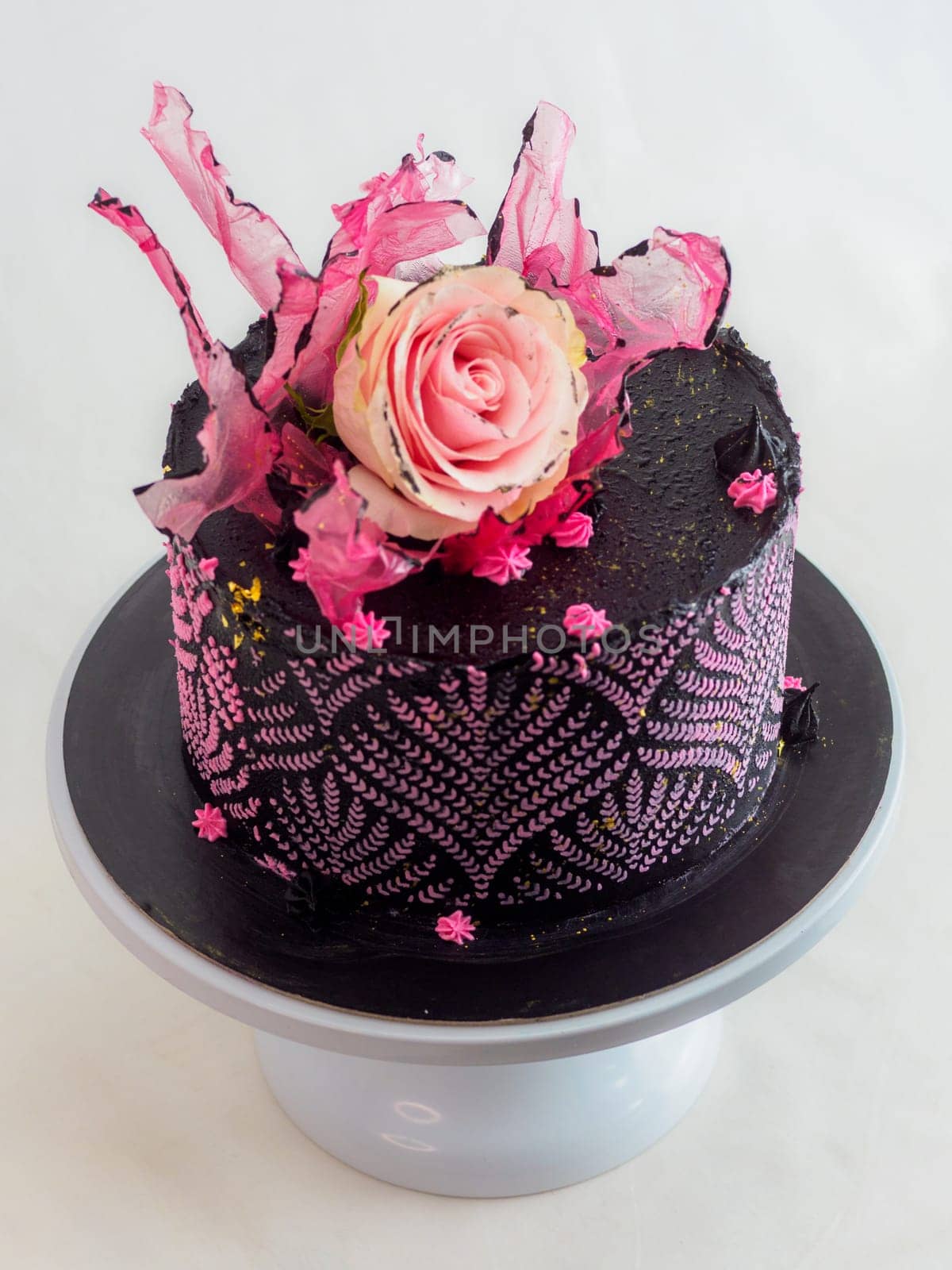 frosted icing black decorate cake for birthday celebration, real rose topping and pink sweet swirls by verbano