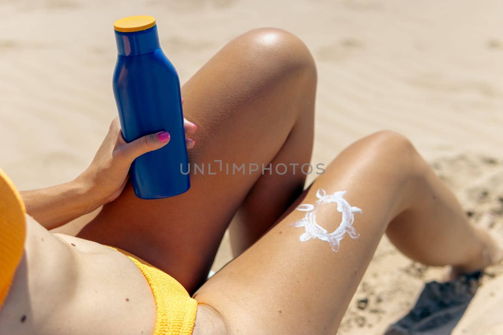 Sunscreen for skin care. Close-up of woman's legs applying sun lotion before sunbathing. Beautiful dark-skinned woman applies cream on her tanned leg . high quality photo. High quality photo