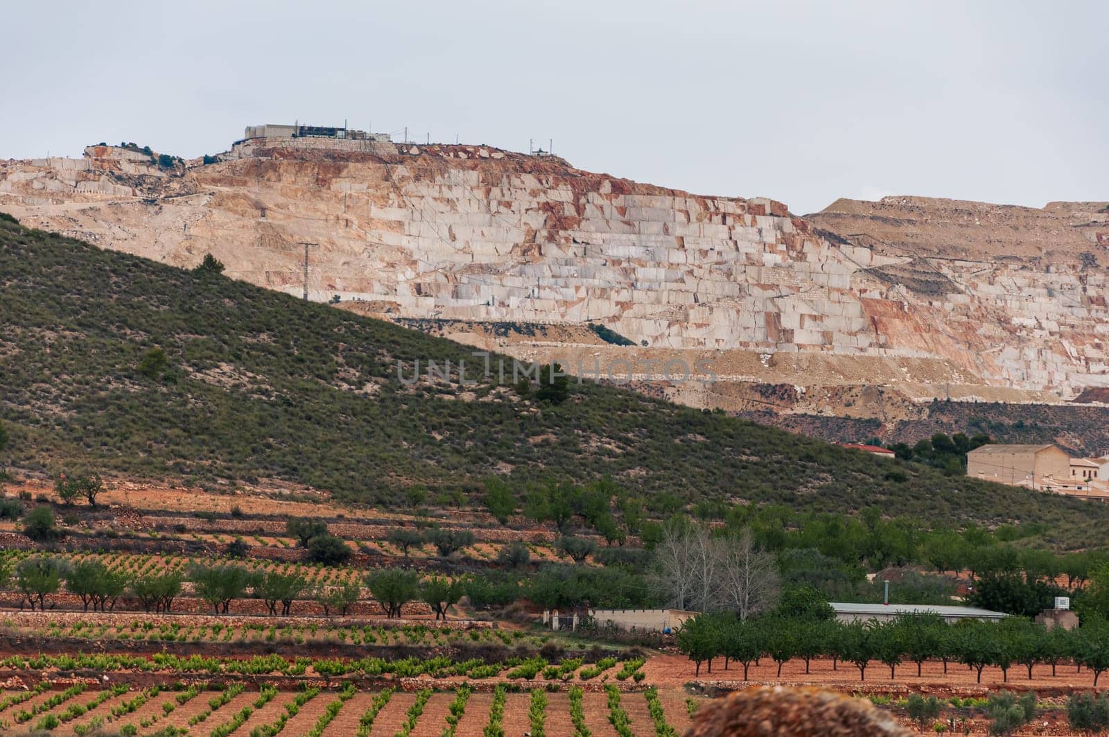 Landscape view of an open cast marble quarry showing heavy duty equipment and rock. High quality photo