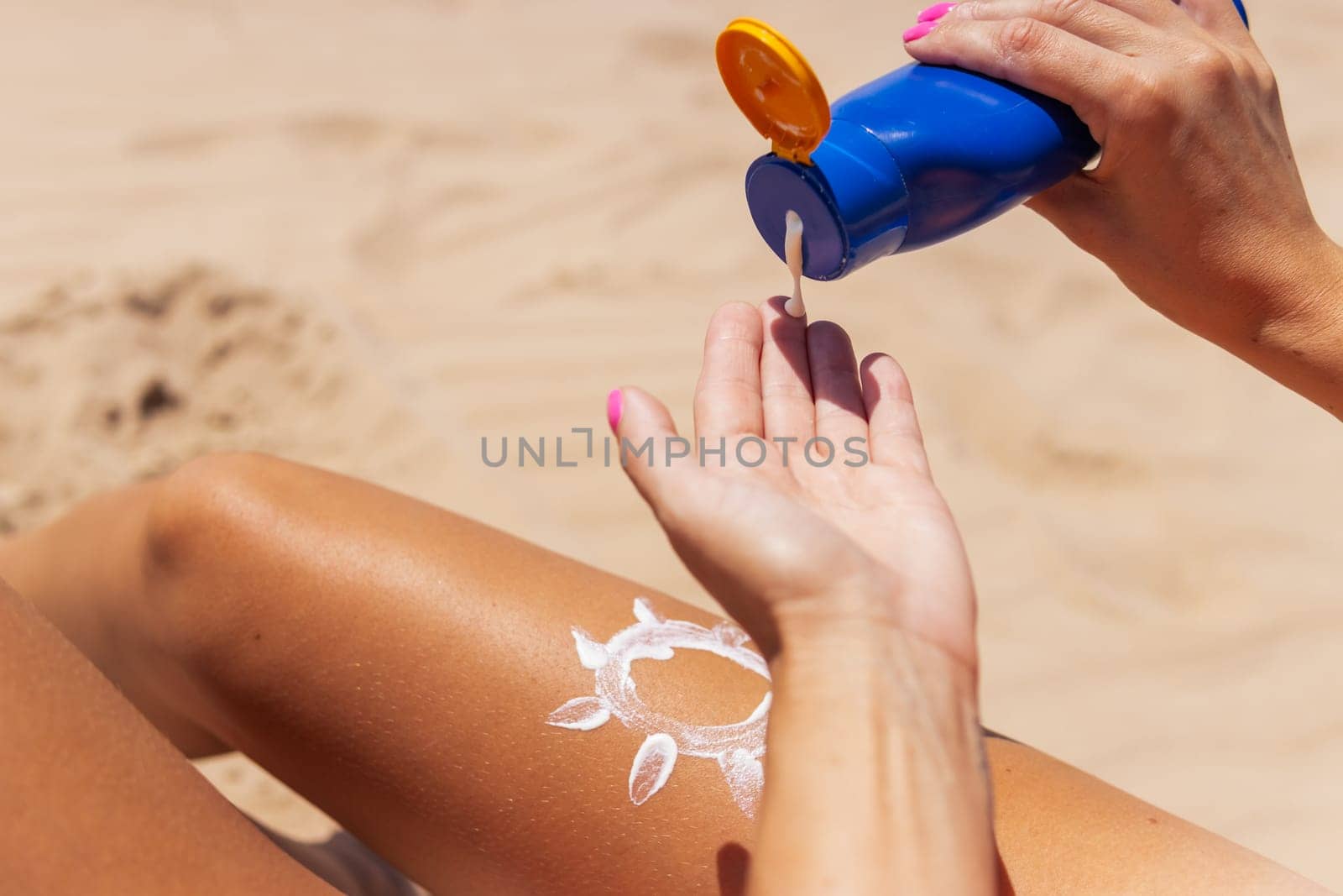 A woman smears sunscreen with moisturizing lotion on her smooth tanned legs. The girl is holding by PopOff