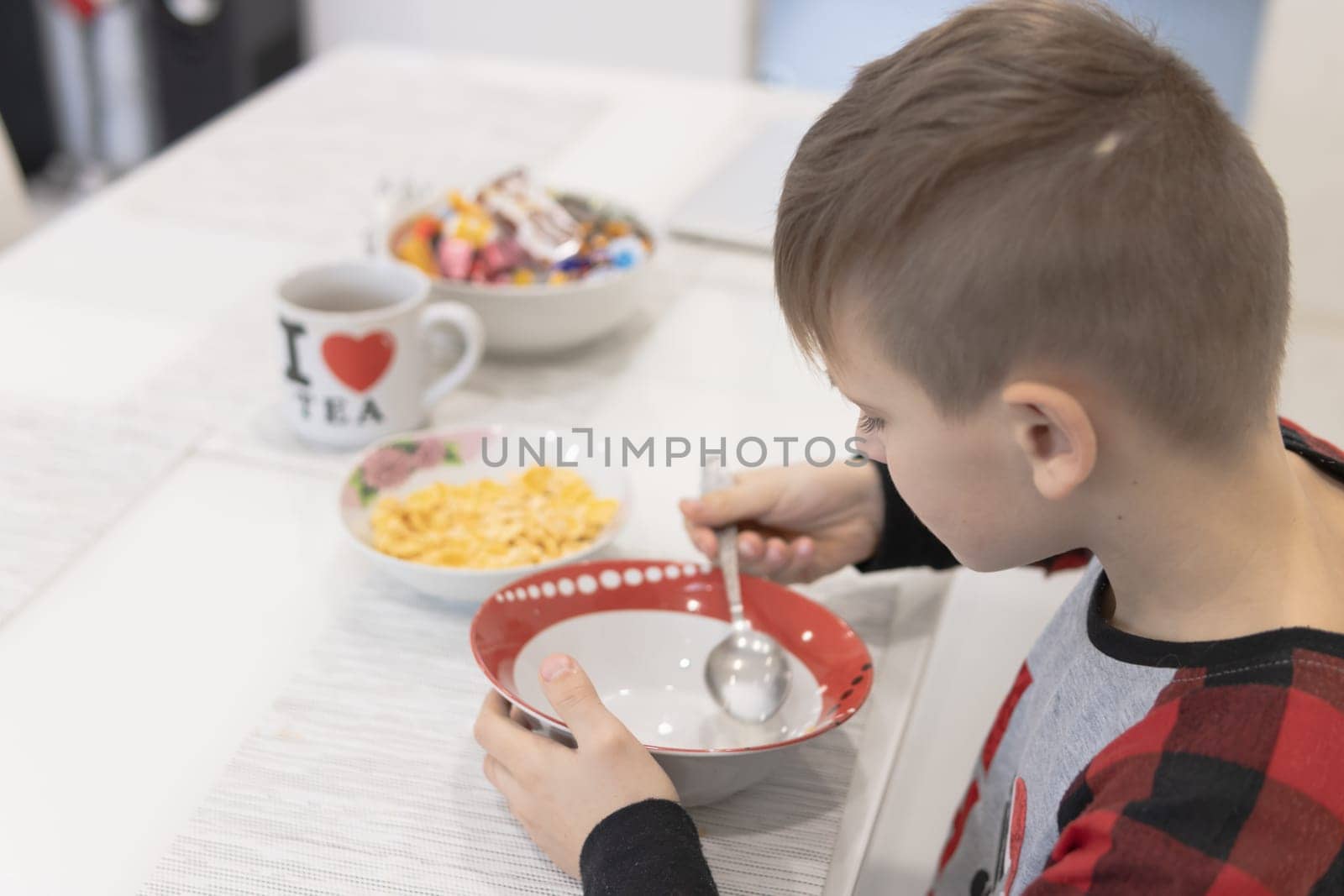 Child having breakfast. Kid drinking milk and eating cereal with fruit by PopOff