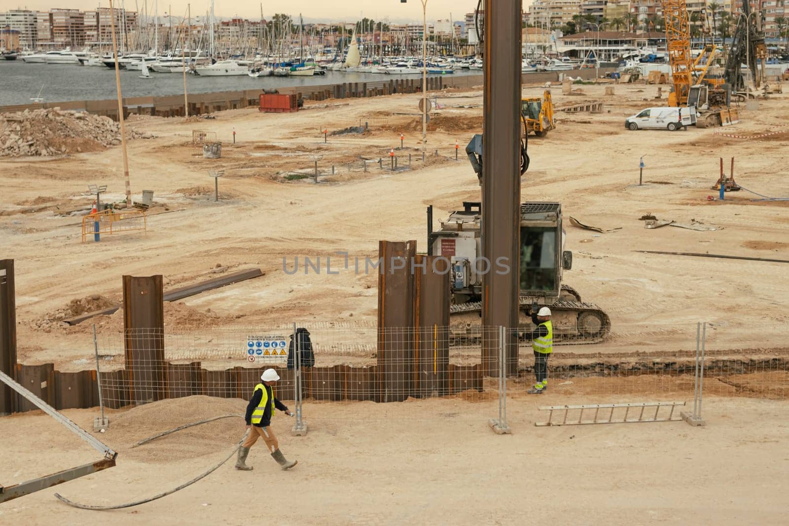 construction site near the pier with yachts, there are a lot of equipment at the construction site, various cranes and cars are standing. High quality photo